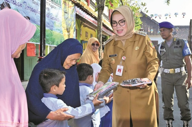 TEBAR KEBAHAGIAAN: Bupati Sukoharjo Etik Suryani (kanan) memberikan hadiah kepada anak-anak dalam sebuah kunjungan kerja. (IWAN KAWUL/RADAR SOLO)