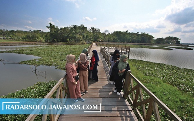 LEBIH CANTIK: Pengunjung menikmati suasana sore hari di Waduk Cengklik dari atas jembatan kayu yang berada di atas air kemarin (9/6/2023). (ARIEF BUDIMAN/RADAR SOLO)