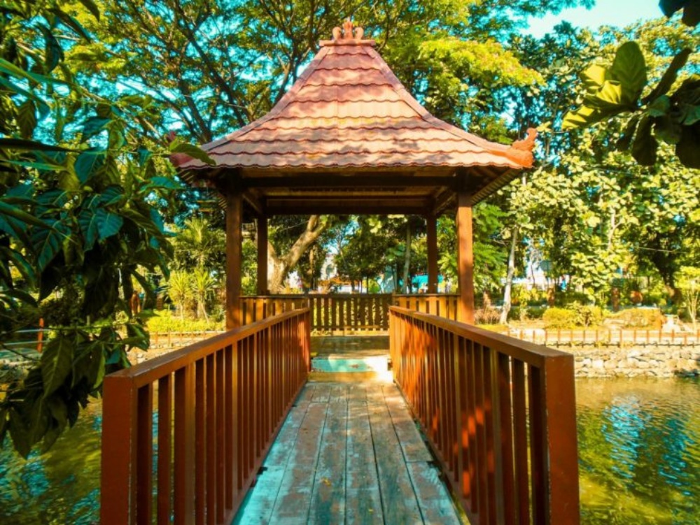 Jembatan kayu dan gazebo di atas kolam. (foto: travelingyuk.com)