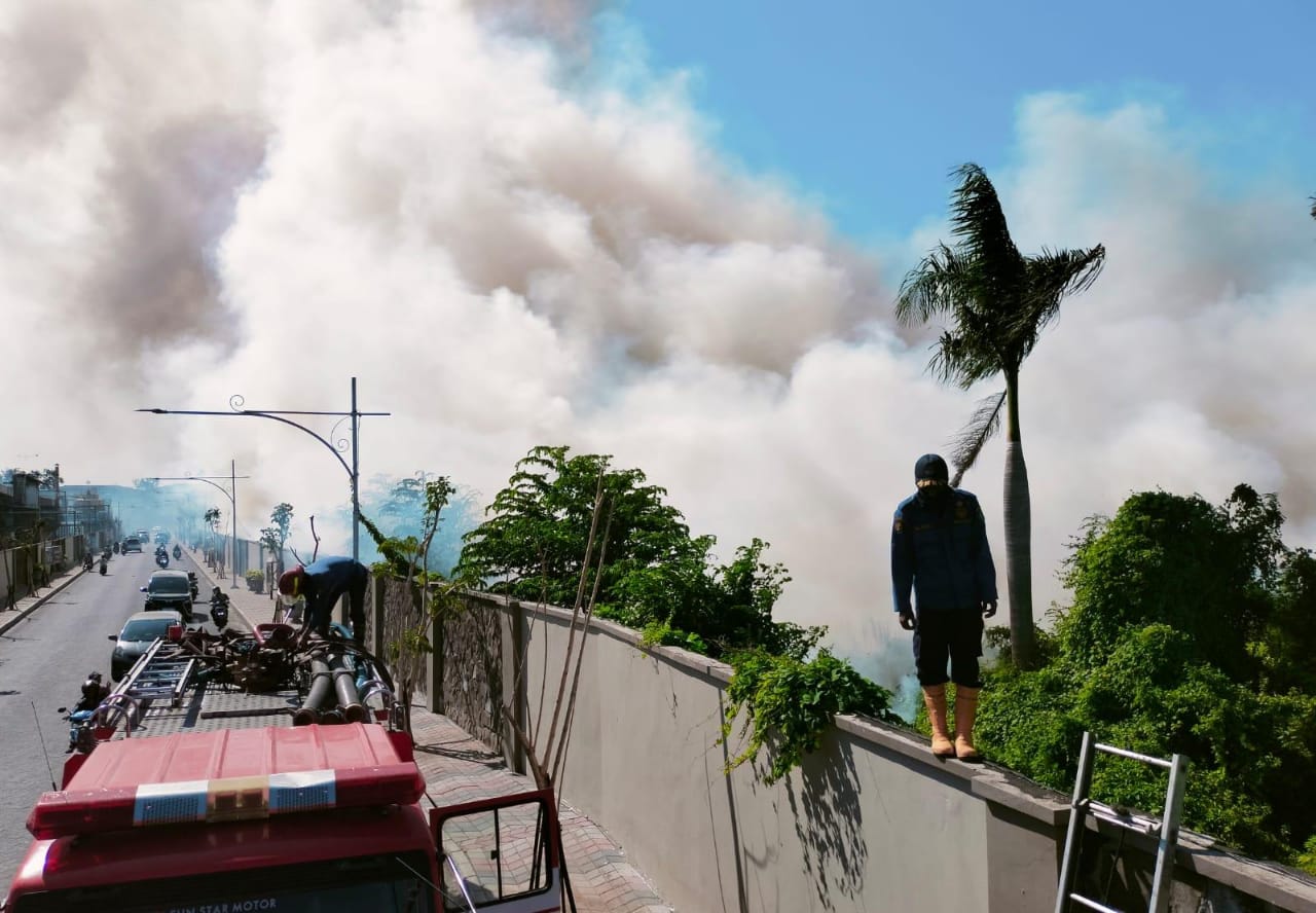 ASAP TEBAL : Petugas damkar memanjat dinding untuk memadamkan api di lahan kosong. (DIKY PUTRA SANSIRI/RADAR SIDOARJO)  &nbsp;