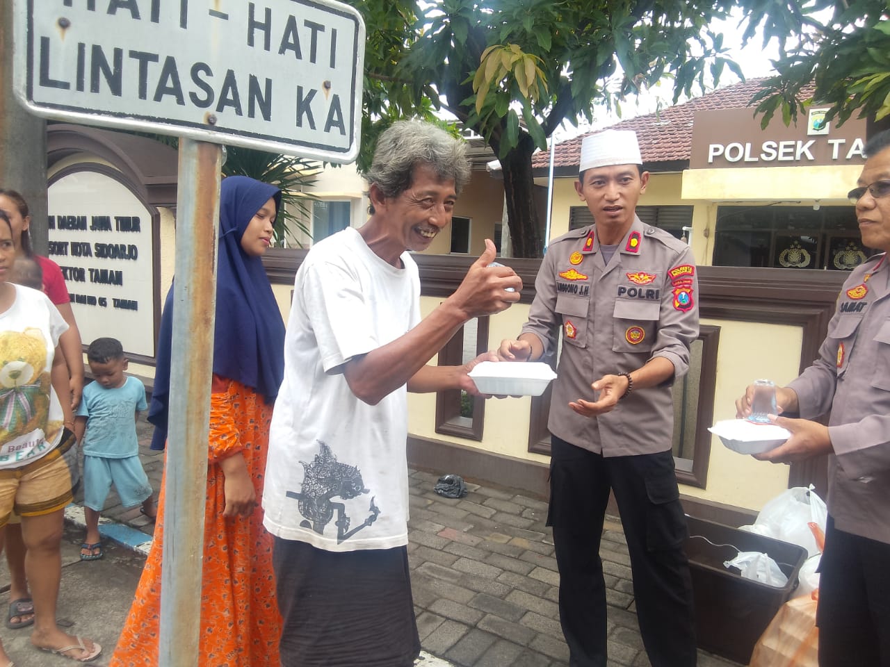 SOSIAL : Kapolsek Taman Kompol Anggono Jaya didampingi Wakapolsek Taman AKP Samat membagikan nasi bungkus kepada masyarakat. (DIKY PUTRA SANSIRI/RADAR SIDOARJO)