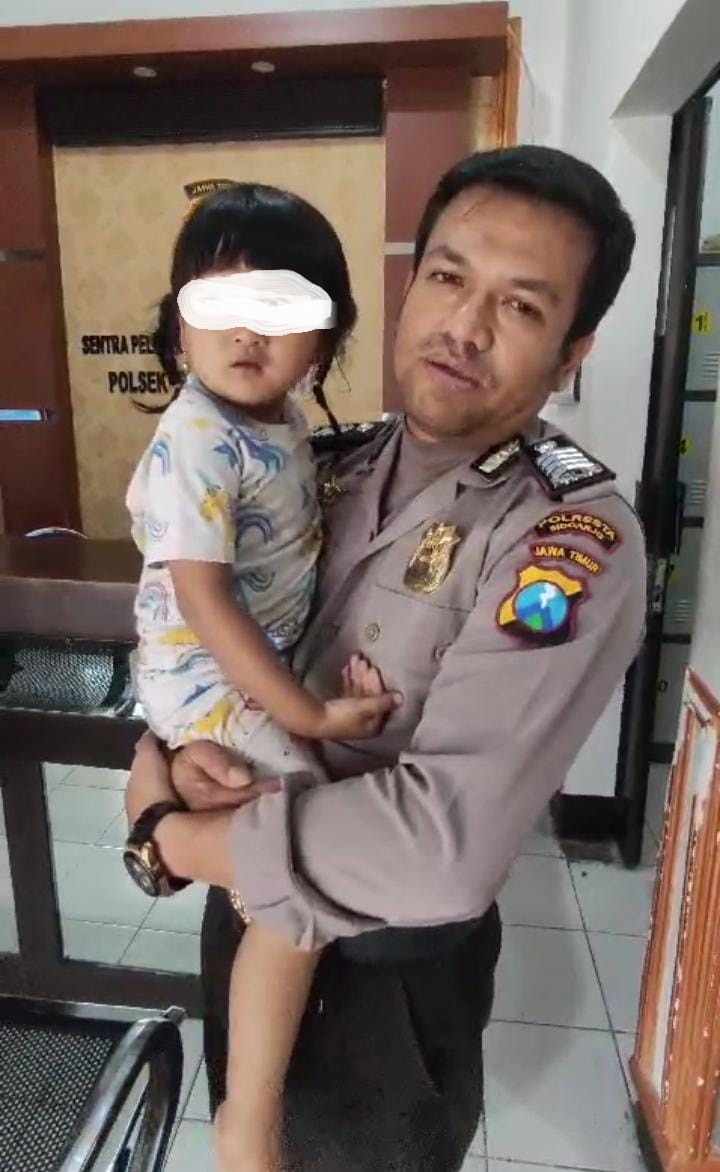 SEMPAT WASWAS: Bocah perempuan yang sempat hilang digendong polisi. (IST)