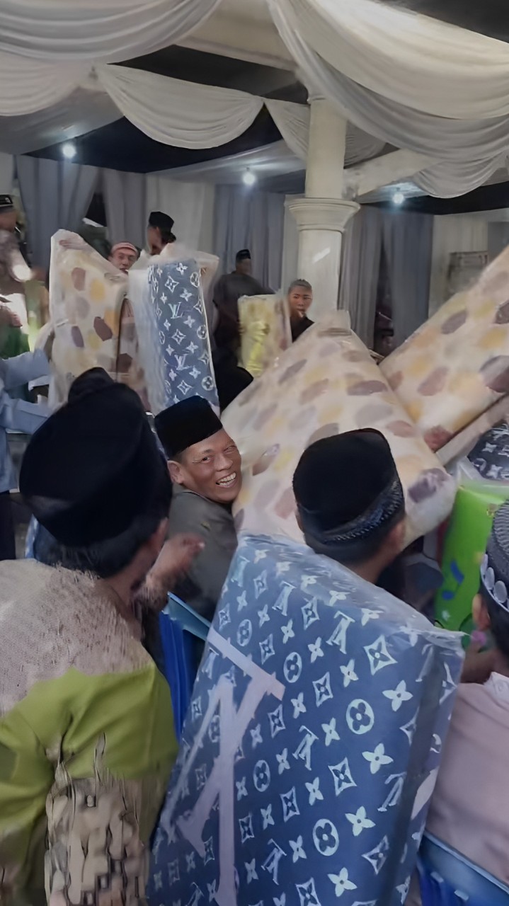 SUMRINGAH: Bapak-bapak yang menghadiri walimahan di Sedati, Sidoarjo, membawa pulang kasur lipat sebagai souvenir. (IST/akun TikTok @mas_kemon03)
