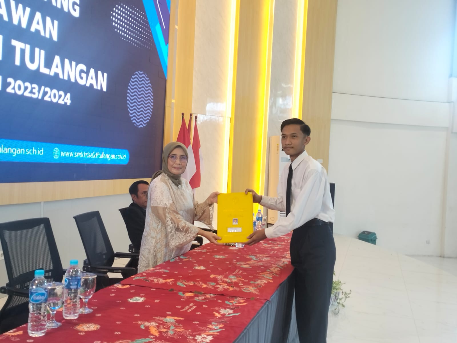 SELAMAT: Kepala SMK Trisakti Tulangan Sidoarjo Sulis Setiawati saat menyerahkan ijazah siswa dalam prosesi wisuda.  (ANAS/RADAR SIDOARJO)