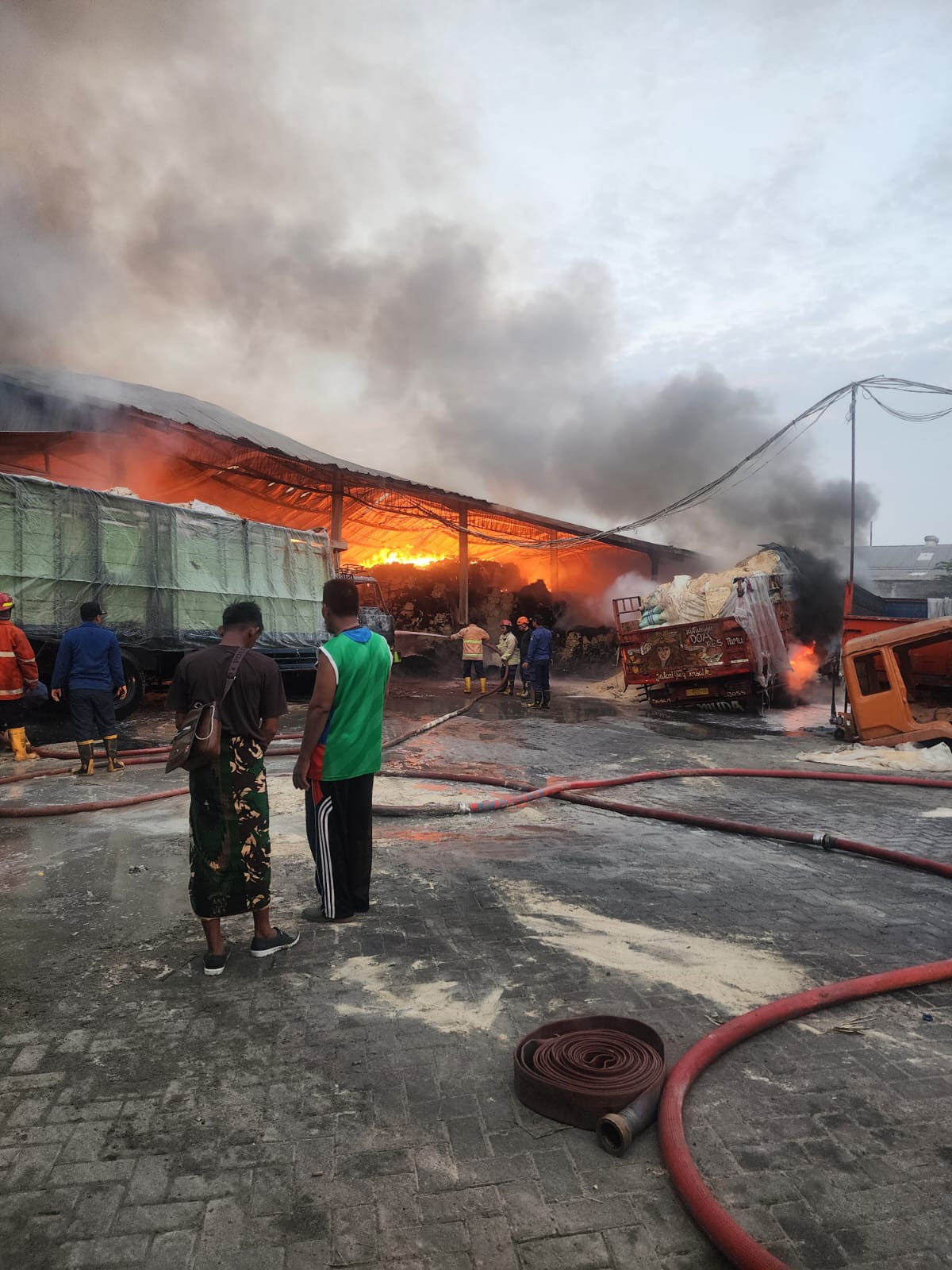 DISIRAM AIR : Petugas damkar masih dalam proses pemadaman Gudang Bekatul, Minggu (23/6). (DIKY PUTRA SANSIRI/RADAR SIDOARJO)
