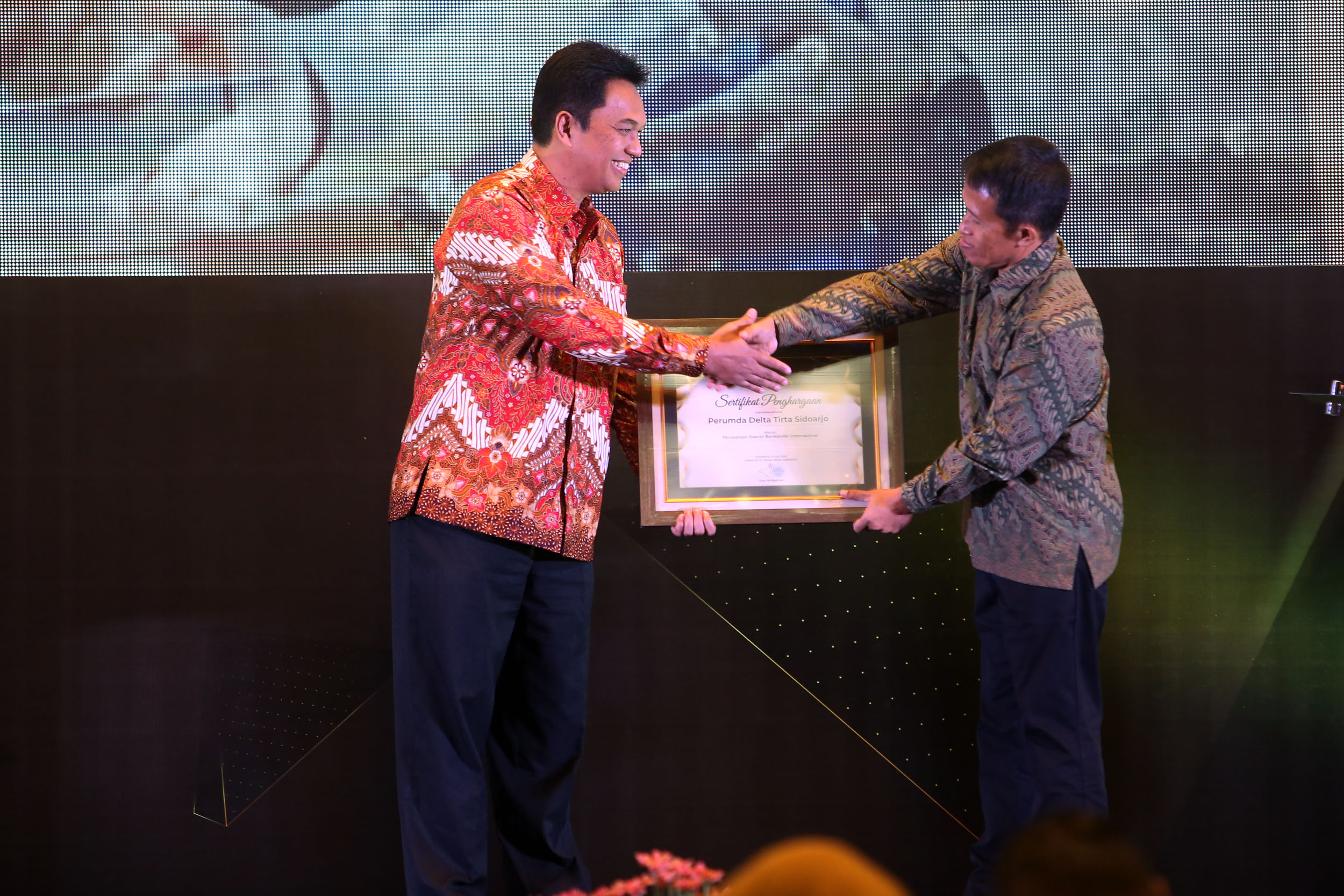 SELAMAT: Direktur Utama PDAM Sidoarjo Dwi Hary Soeryadi menerima penghargaan dari Komisaris Radar Surabaya Leak Kustiya. (ANDY SATRIA/RADAR SURABAYA)