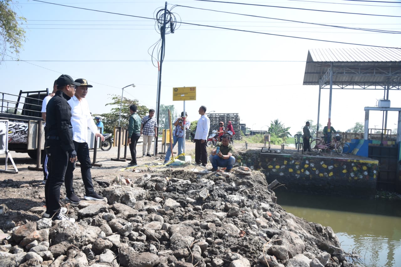 DIKERJAKAN : Plt Bupati Sidoarjo Subandi (baju putih) saat meninjau jembatan ambruk di Kedungpeluk. (FOTO HUMAS KOMINFO)