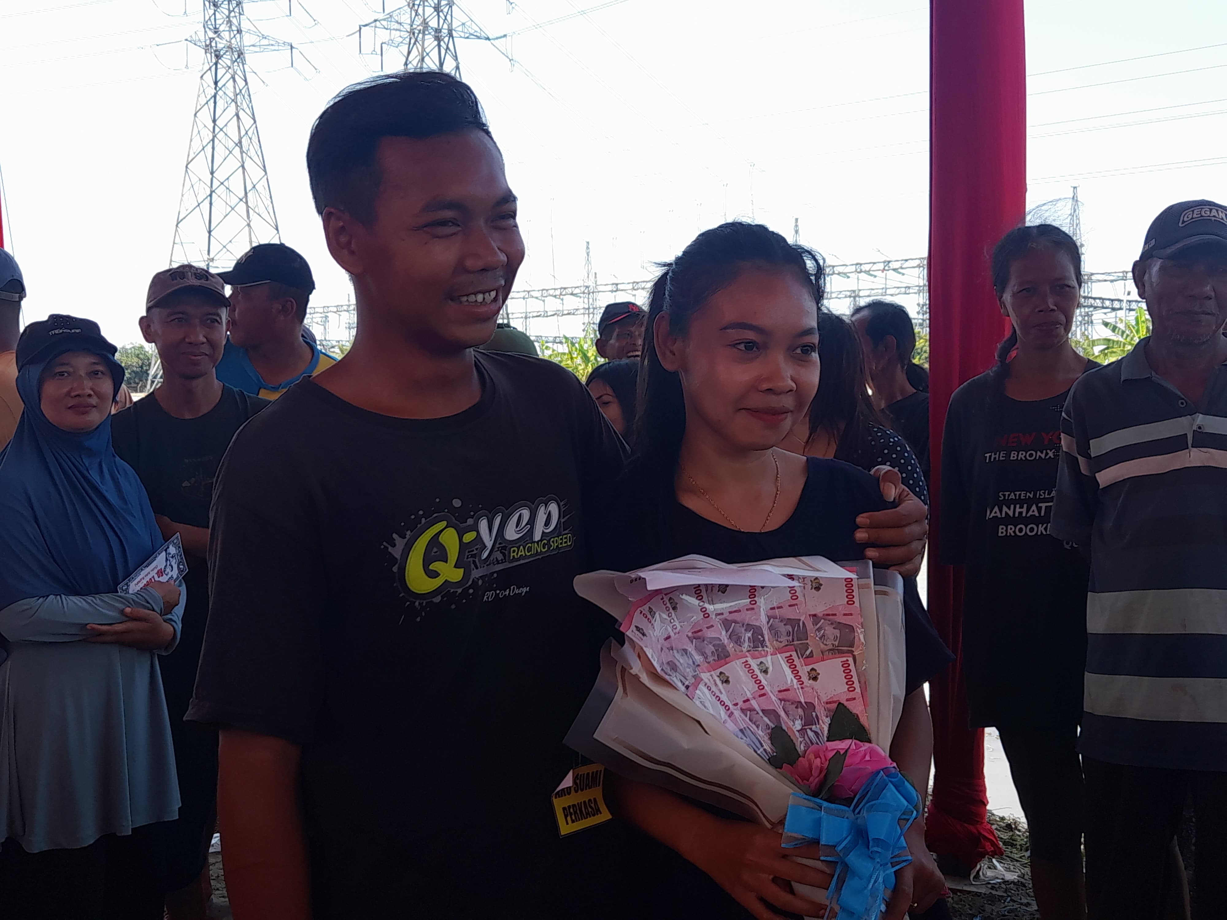 SENANG : Sang juara gendong suami istri saat menerima hadiah. (M SAIFUL ROHMAN/RADAR SIDOARJO)