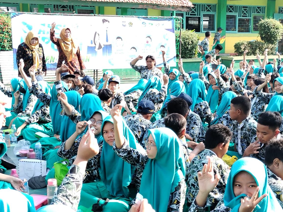 SEMANGAT : Kepala SMP Negeri 3 Taman Dra. Sumarti, M.Pd saat mengintruksikan minum vitamin dalam kegiatan Aksi Bergizi. (ANAS/RADAR SIDOARJO)