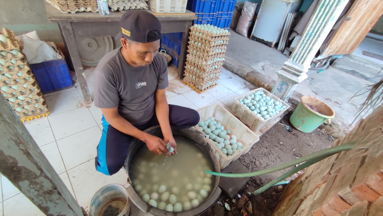 MENURUN: Perajin telur asin di Candi sedang membersihkan telur untuk dijual. (M SAIFUL ROHMAN/RADAR SIDOARJO)