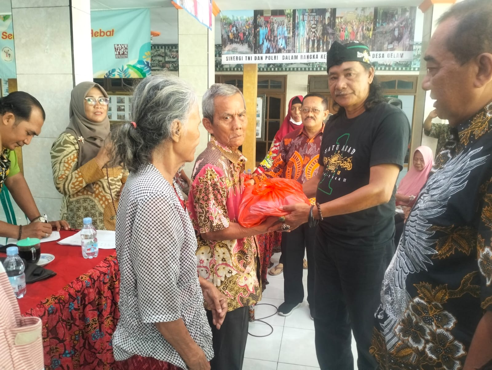 PEDULI: Kades Gelam Muchammad Muslich (tengah) memberikan bantuan sembako ke warga terdampak banjir. (ANAS/RADAR SIDOARJO)