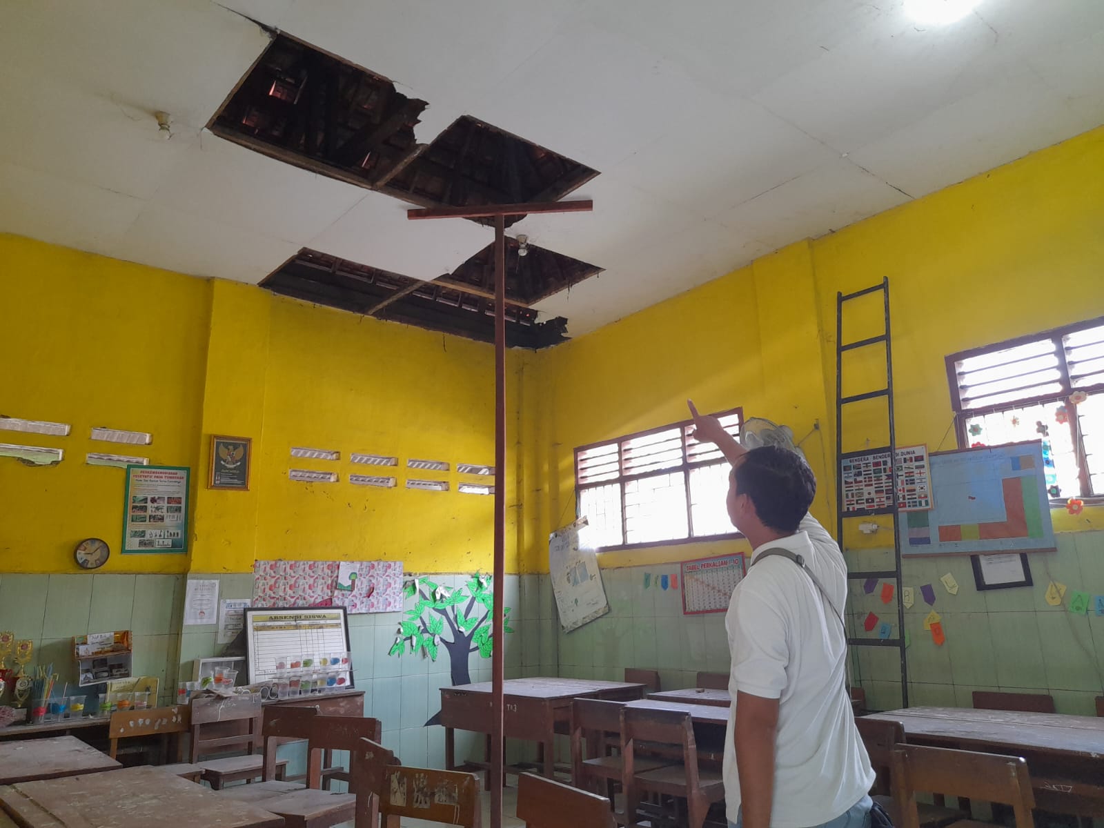 JEBOL : Anggota komisi D DPRD Sidoarjo Pujiono saat meninjau atap SDN Sidomojo yang ambruk. (M SAIFUL ROHMAN/RADAR SIDOARJO)