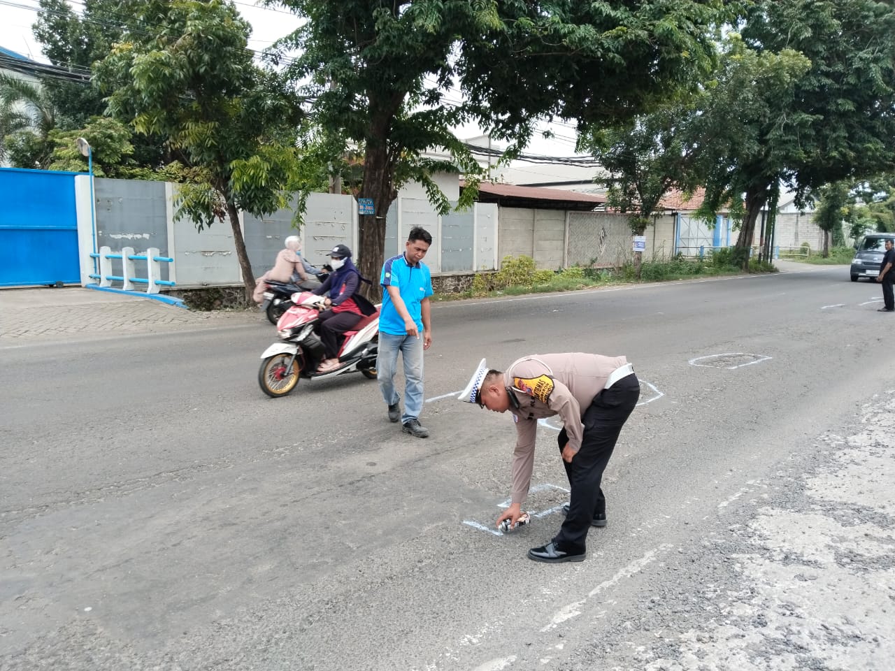 DITANDAI : Unit Lantas Polsek Balongbendo memberi cat putih pada aspal jalan yang rusak di Jalan Kemangsen-Jabaran, Sidoarjo. (IST/RADAR SURABAYA)