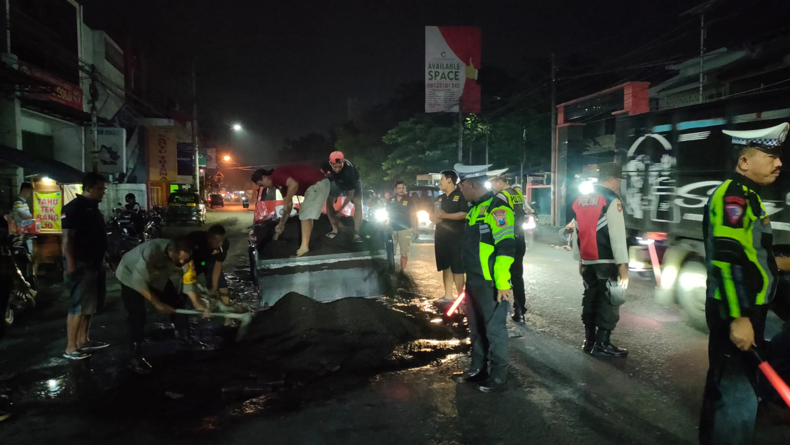 GOTONG ROYONG : Relawan bersama Polsek Krian bahu membahu perbaiki jalan rusak di depan Pasar Krian, Sidoarjo, Sabtu (11/1). (IST/RADAR SIDOARJO)