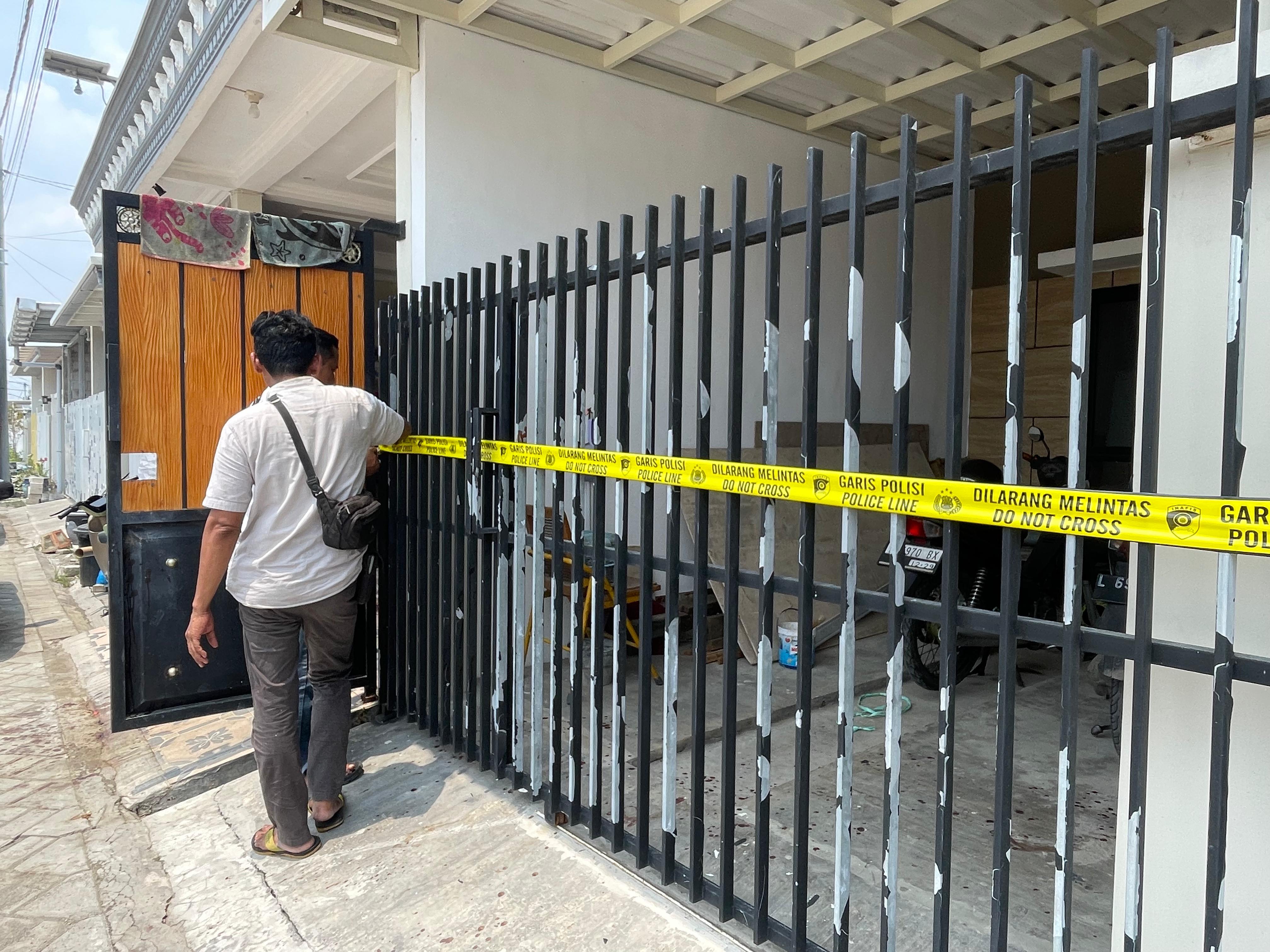 DIPASANG : Anggota Polsek Waru memasang garis polisi di rumah korban Perumahan Alana Regency, Tambakoso, Waru, Sidoarjo. (DIKY PUTRA SANSIRI/RADAR SIDOARJO)