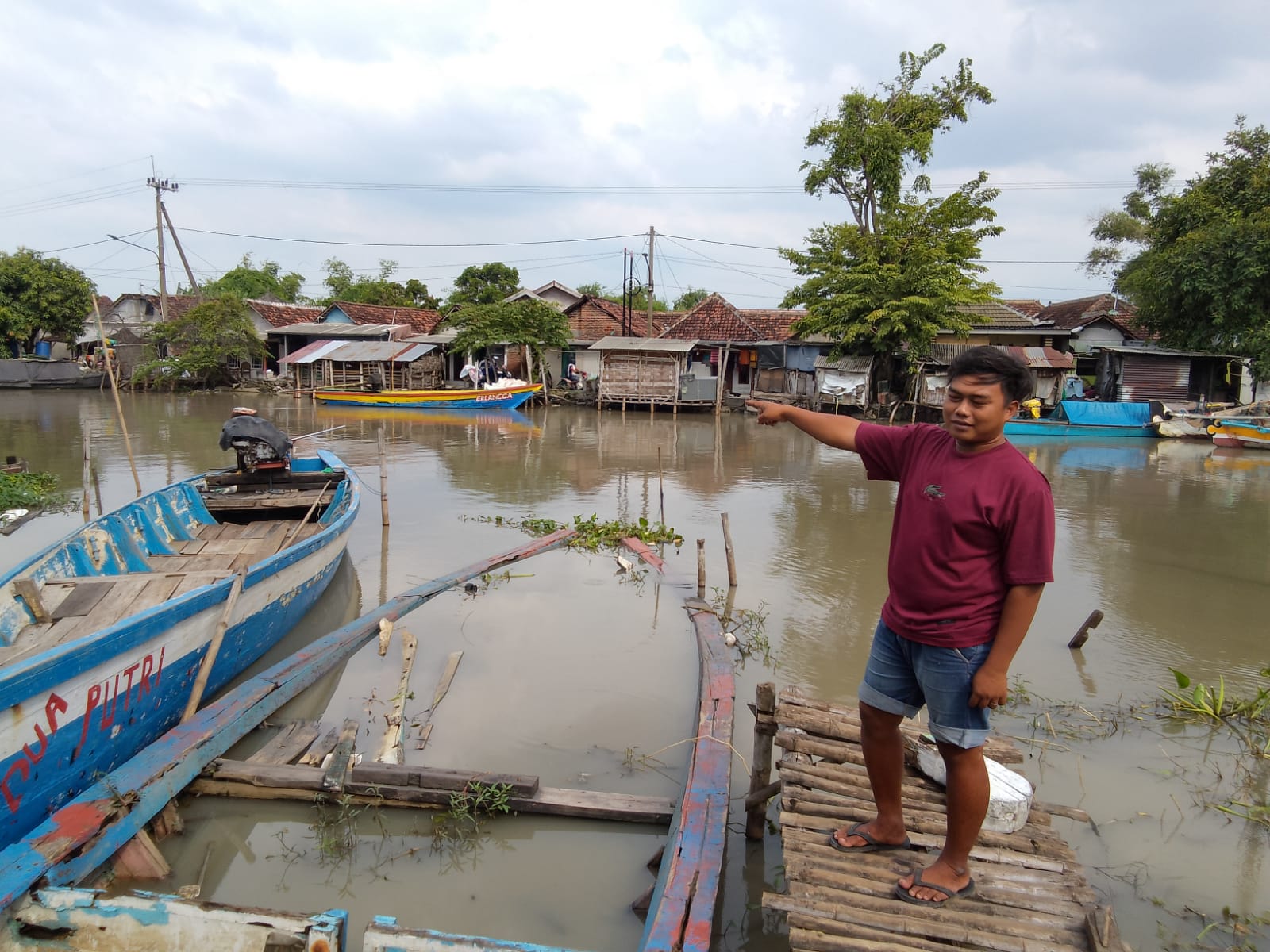 TONTONAN : Salah satu warga, Fadli menunjukkan lokasi kemunculan tiga buaya di sungai Desa Kedungpeluk, Sidoarjo, Senin (20/1). (IST/RADAR SIDOARJO)