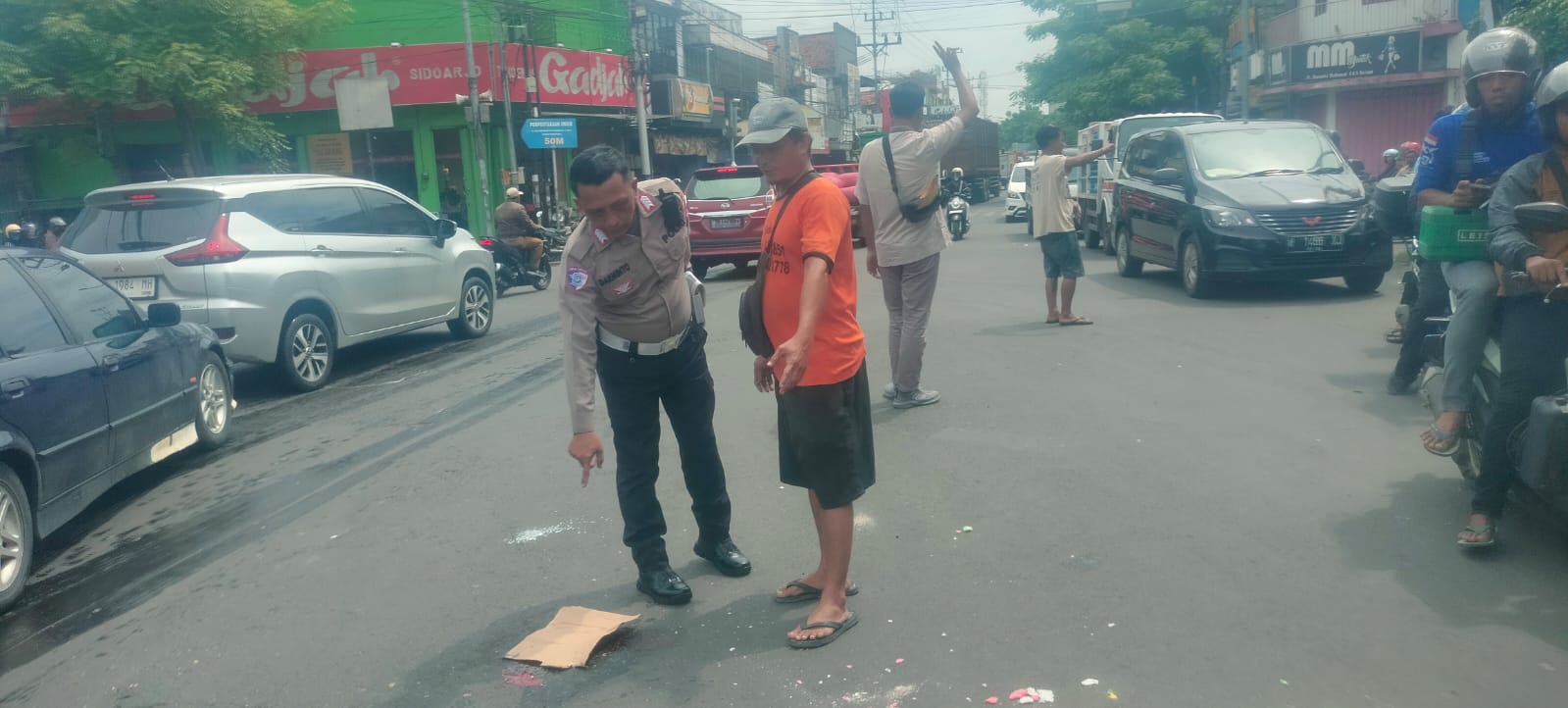 MENINGGAL : petugas menunjukkan lokasi kecelakaan antara sepeda motor dengan truk tangki di Simpang Lima Krian, Sidoarjo, Senin (20/1). (IST/RADAR SIDOARJO)