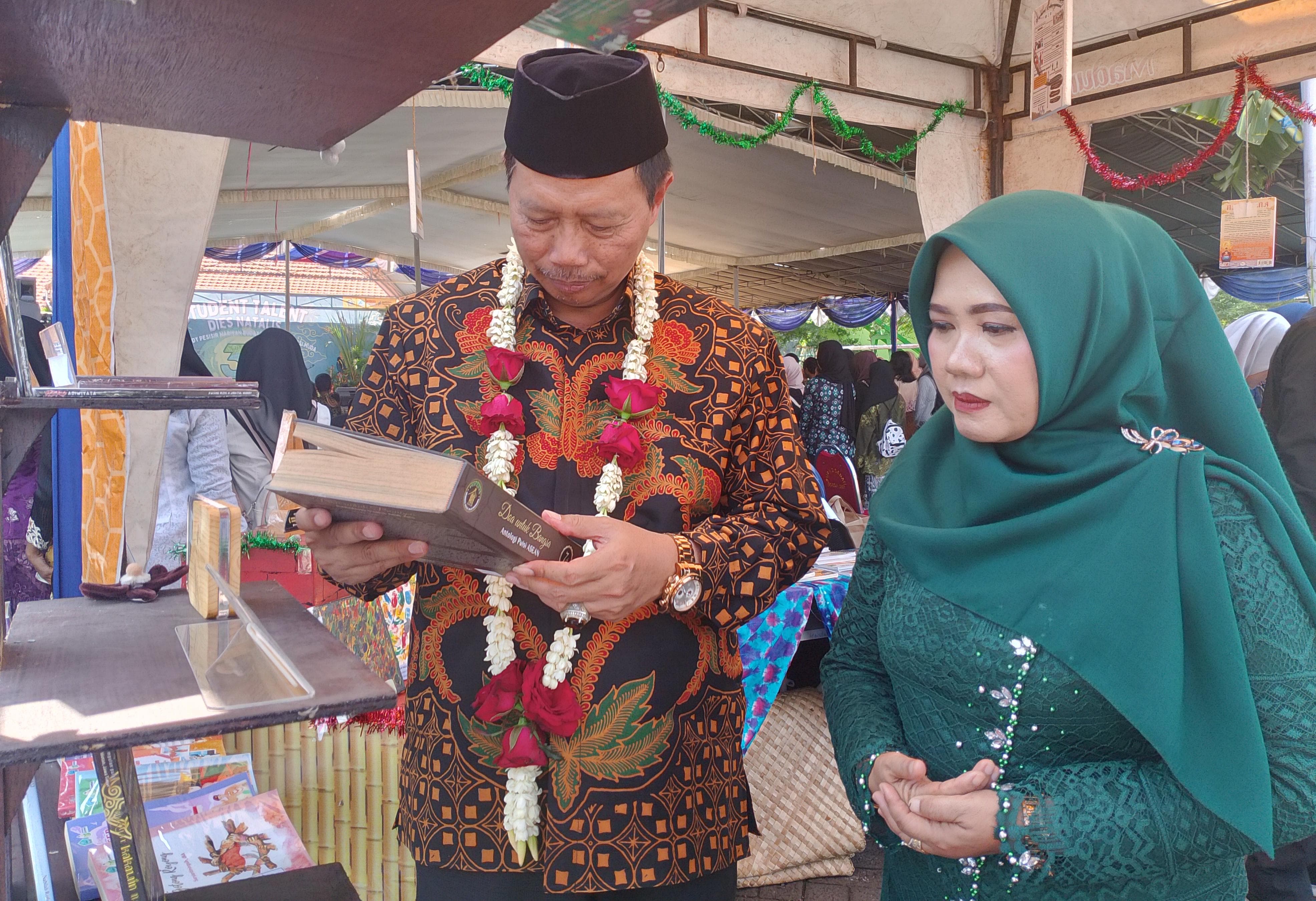 KOLABORASI: Kadispendikbud Dr. Tirto Adi, M.Pd membaca buku hasil kolaborasi guru dan siswa Spendati Sidoarjo yang di launching di acara puncak Dies Natalis ke 39. (INDRA WIJAYANTO/RADAR SIDOARJO)