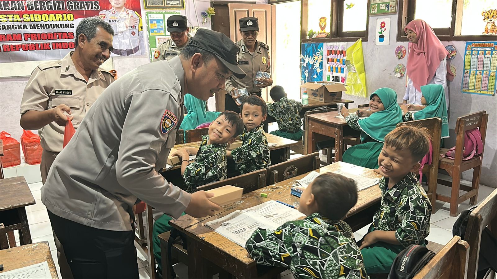 GEMBIRA : Siswa SDN 1 Jogosatru, Sukodono, Sidoarjo, saat mendapat MBG dari Polsek Sukodono. (IST/RADAR SIDOARJO)