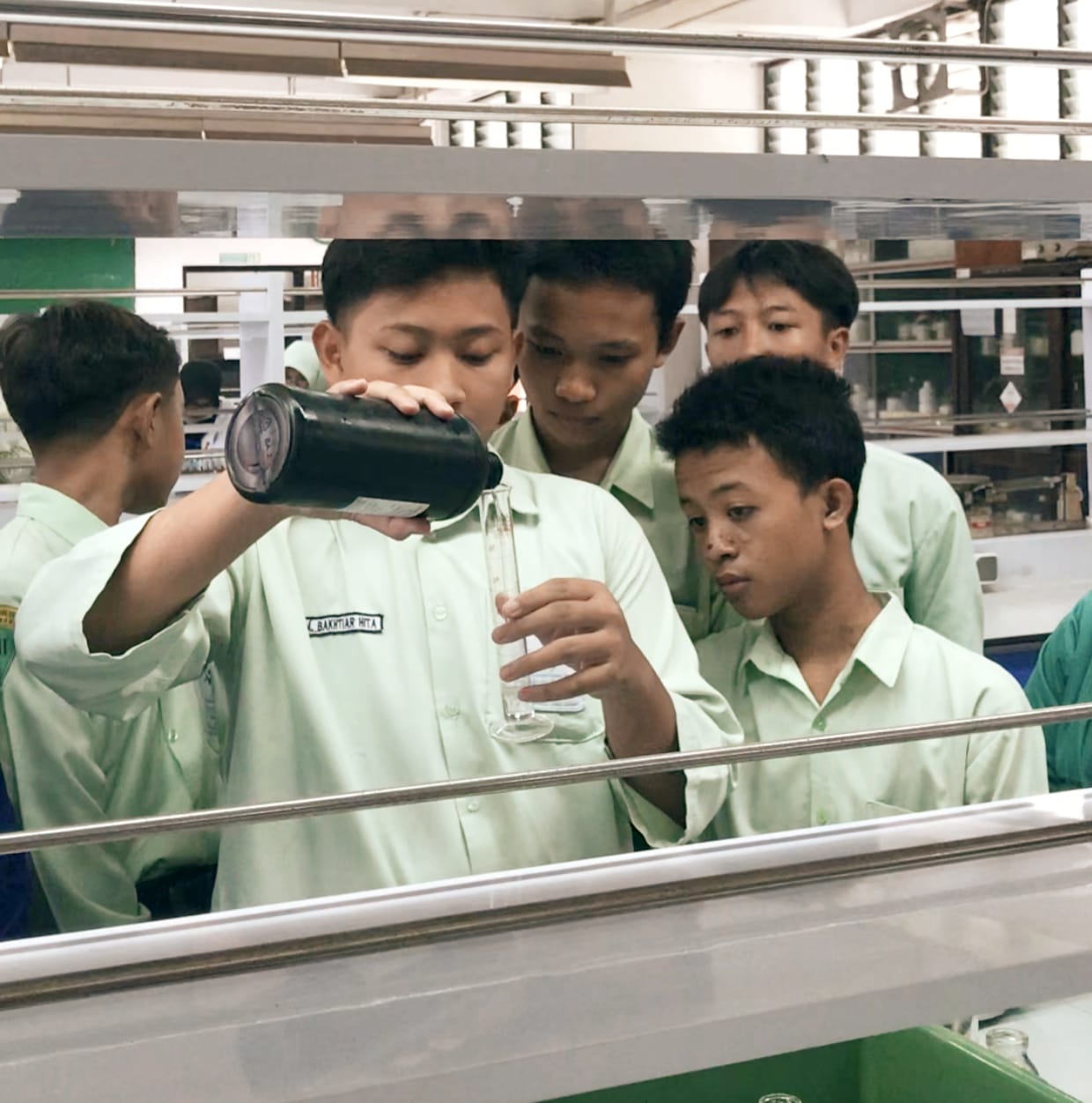 ANTUSIAS: Bachtiar, siswa SMPIT Nurul Islam Sidoarjo sedang menuangkan hidrogen peroksida (H₂O₂) dalam eksperimen di Laboratorium Fundamental Kimia ITS. (ANAS/RADAR SIDOARJO)
