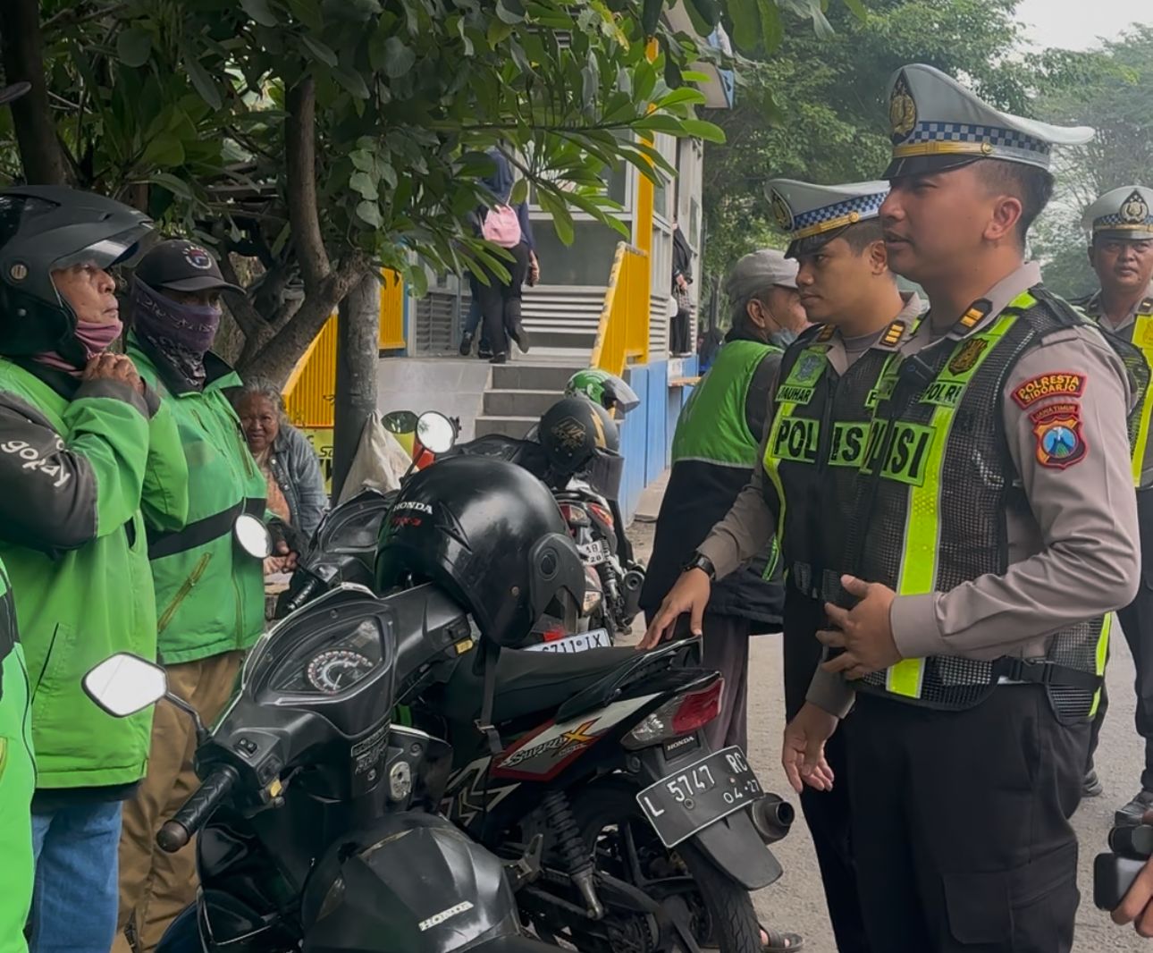 PENERTIBAN : Satlantas Polresta Sidoarjo mengimbau pengendara ojol agar tidak menurunkan atau mengambil penumpang sembarangan di pintu keluar bus Terminal Purabaya, Sidoarjo. (IST/RADAR SIDOARJO)