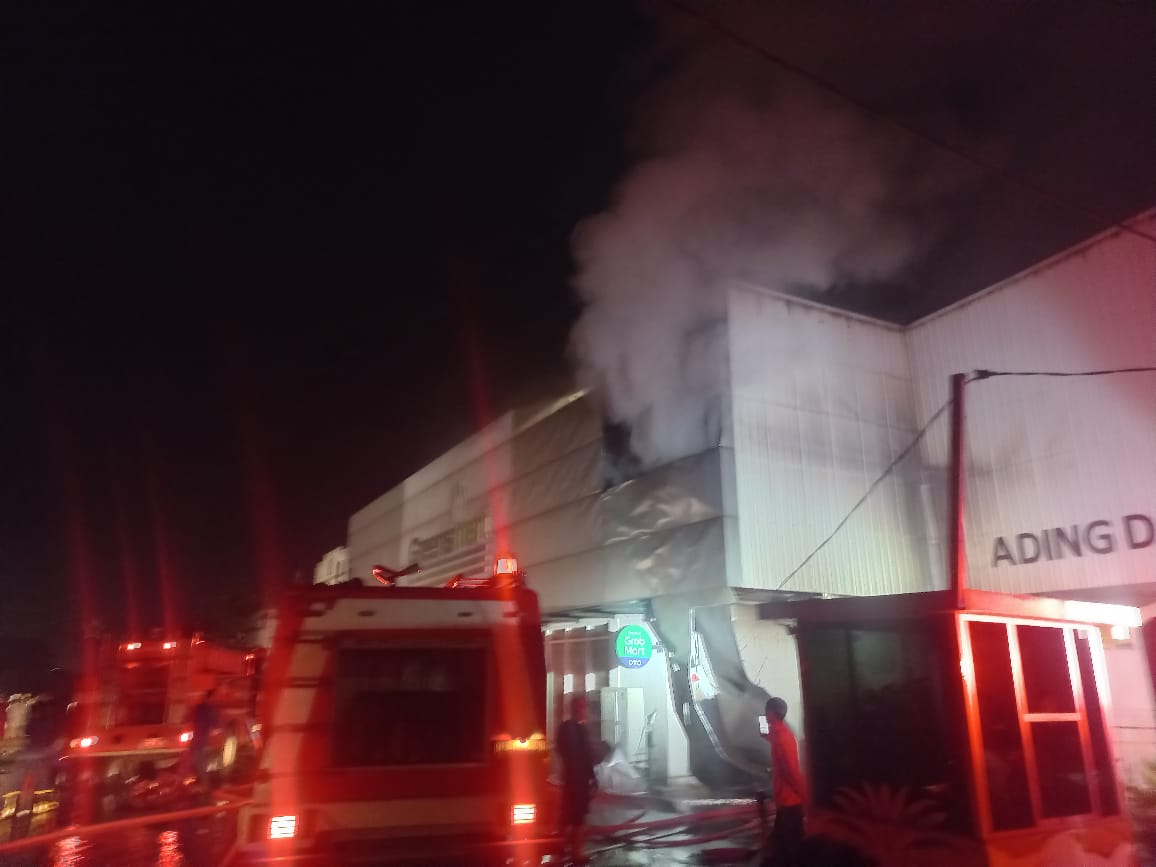 MENYALA : Petugas damkar melakukan pemadaman api yang membakar minimarket di Desa Jemundo, Taman, Sidoarjo, Jumat (7/3) malam. (IST/RADAR SIDOARJO)