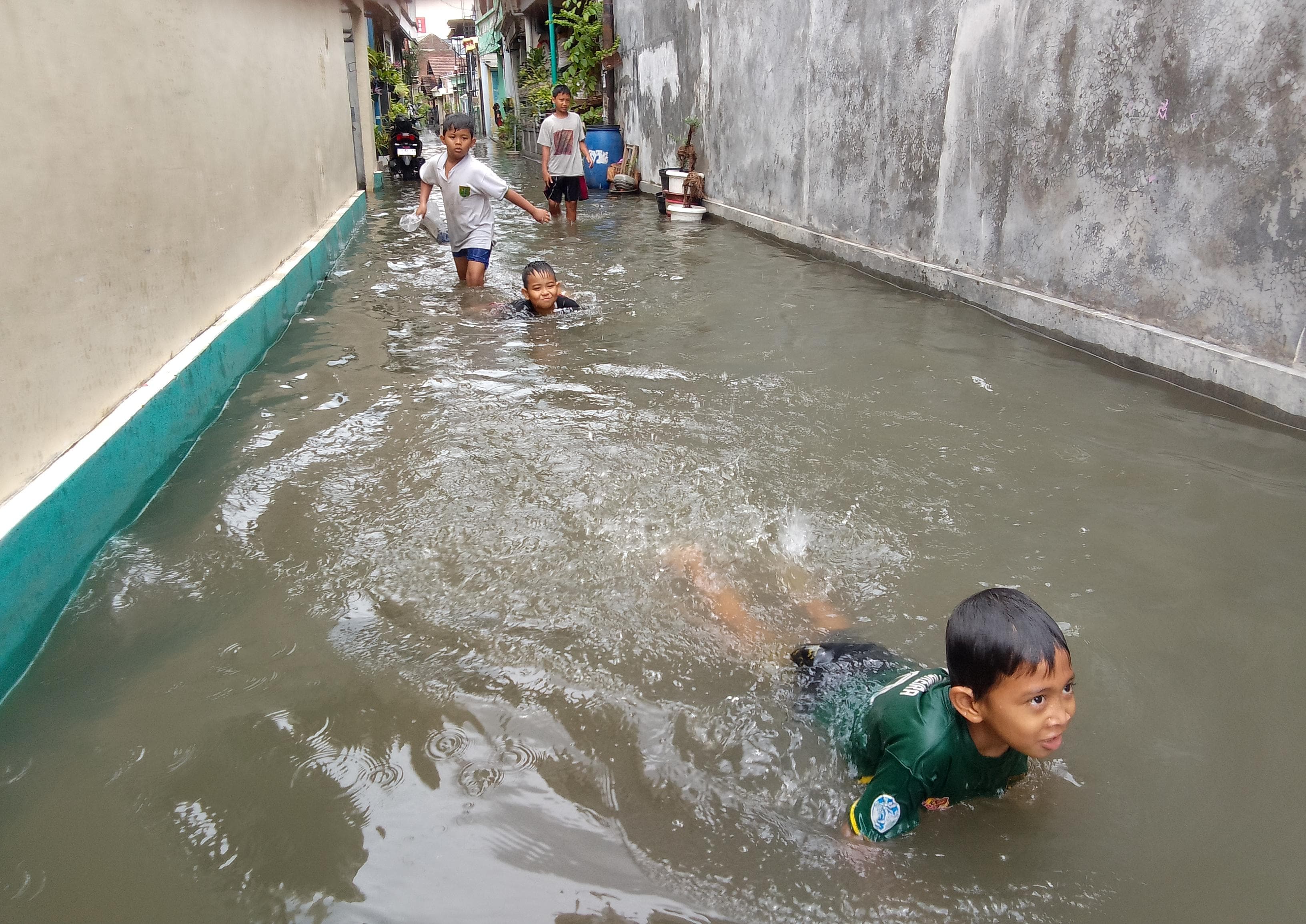 HIBURAN : Bocah di Medaeng, Waru, Sidoarjo, menjadikan banjir sebagai wahana bermain mereka. (DIKY PUTRA SANSIRI/RADAR SIDOARJO)