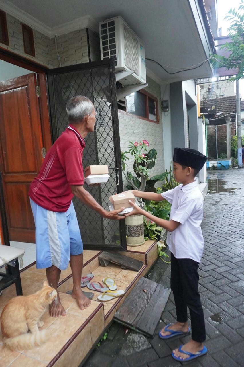 IKHLAS : Salah satu siswa MINU KH Mukmin Sidoarjo saat membagi takjil. (ANAS /RADAR SIDOARJO)