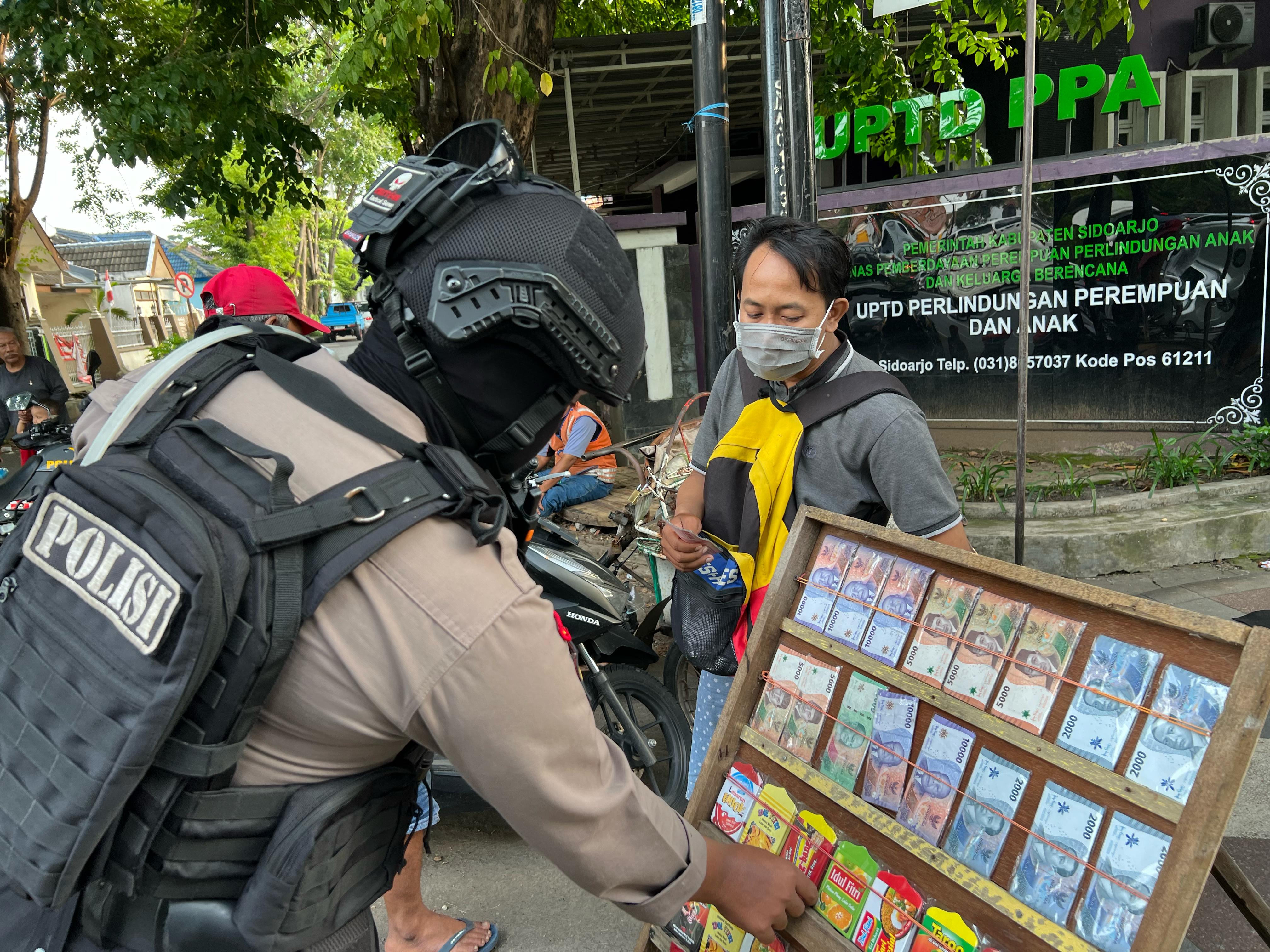 IMBAUAN : Anggota Sat Samapta Polresta Sidoarjo meminta penjual jasa penukaran uang baru berhati-hati selama transaksi. (IST/RADAR SIDOARJO)