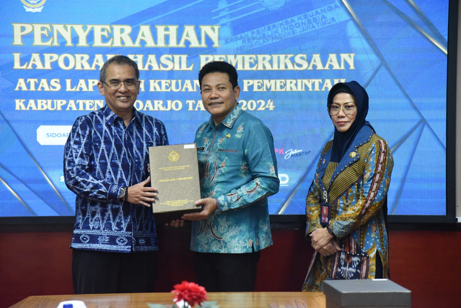 TEPAT WAKTU: Kepala BPK Perwakilan Provinsi Jatim, Yuan Candra Djaisin (kiri) menyerahkan dokumen LHP kepada Bupati Sidoarjo Subandi didampingi oleh Sekda Fenny Apridawati.