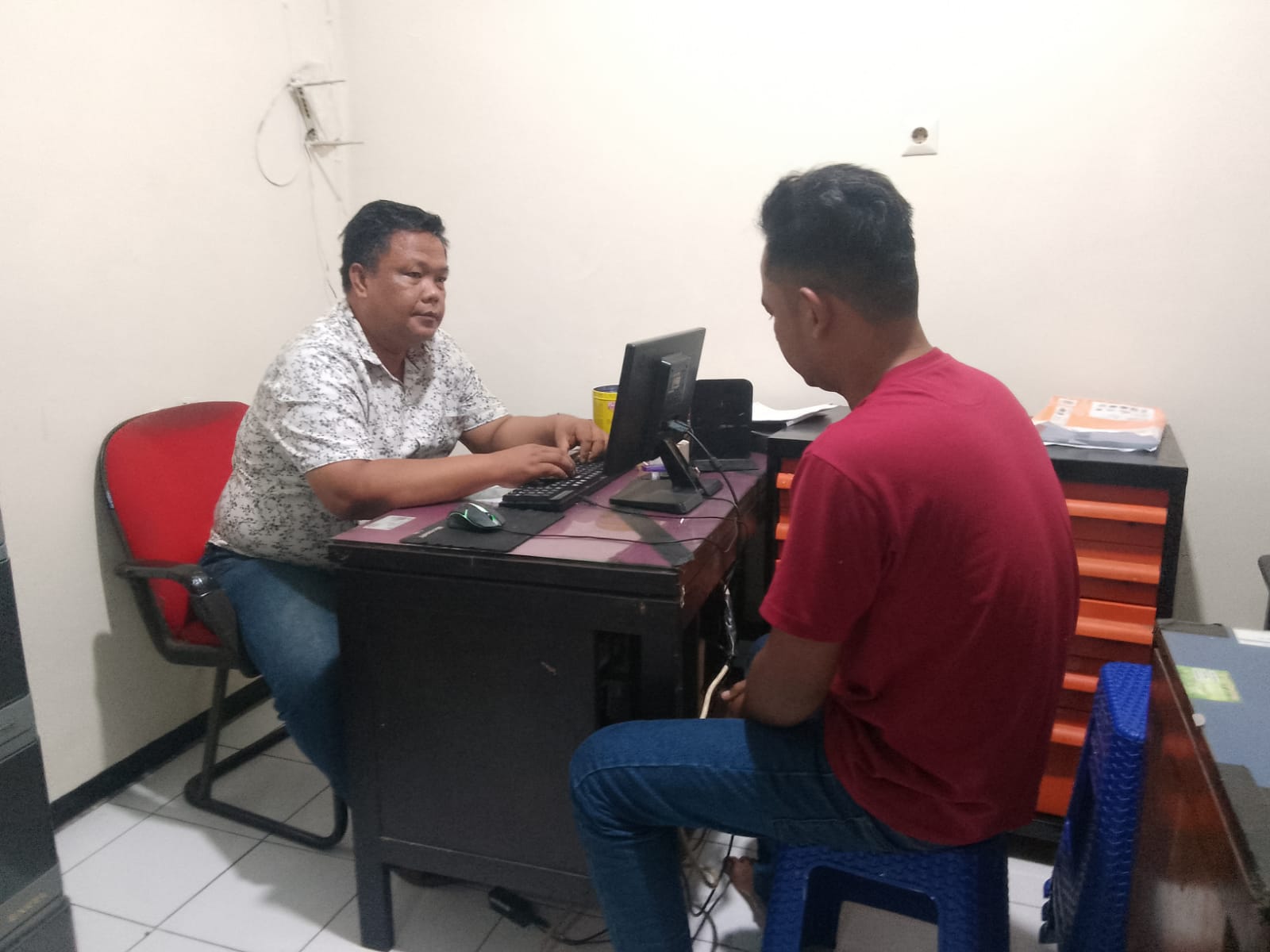 DIAMANKAN : Adi Cahyanto (baju merah) sedang diperiksa oleh penyidik. Pencuri kecap di minimarket, Lajuk, Porong, Sidoarjo, ini ditangkap karyawan setempat. (DIKY SANSIRI/RADAR SIDOARJO)