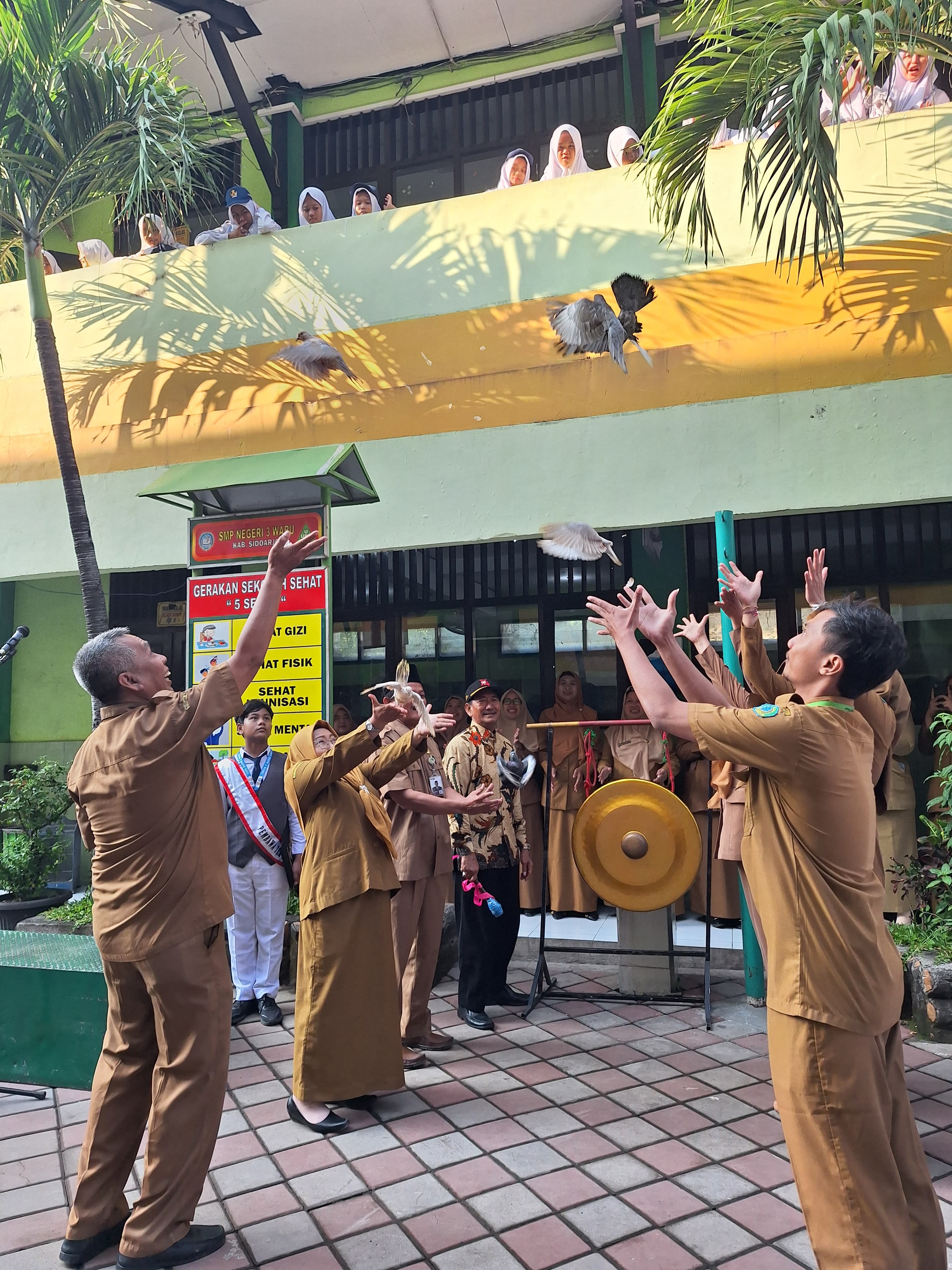 KOMPAK: Pemukulan gong oleh komite sekolah disertai pelepasan merpati oleh kepala SMPN 3 Waru Mas Husein,S.Pd.,M.M.Pd., dan dewan guru. (ANAS/RADAR SIDOARJO)