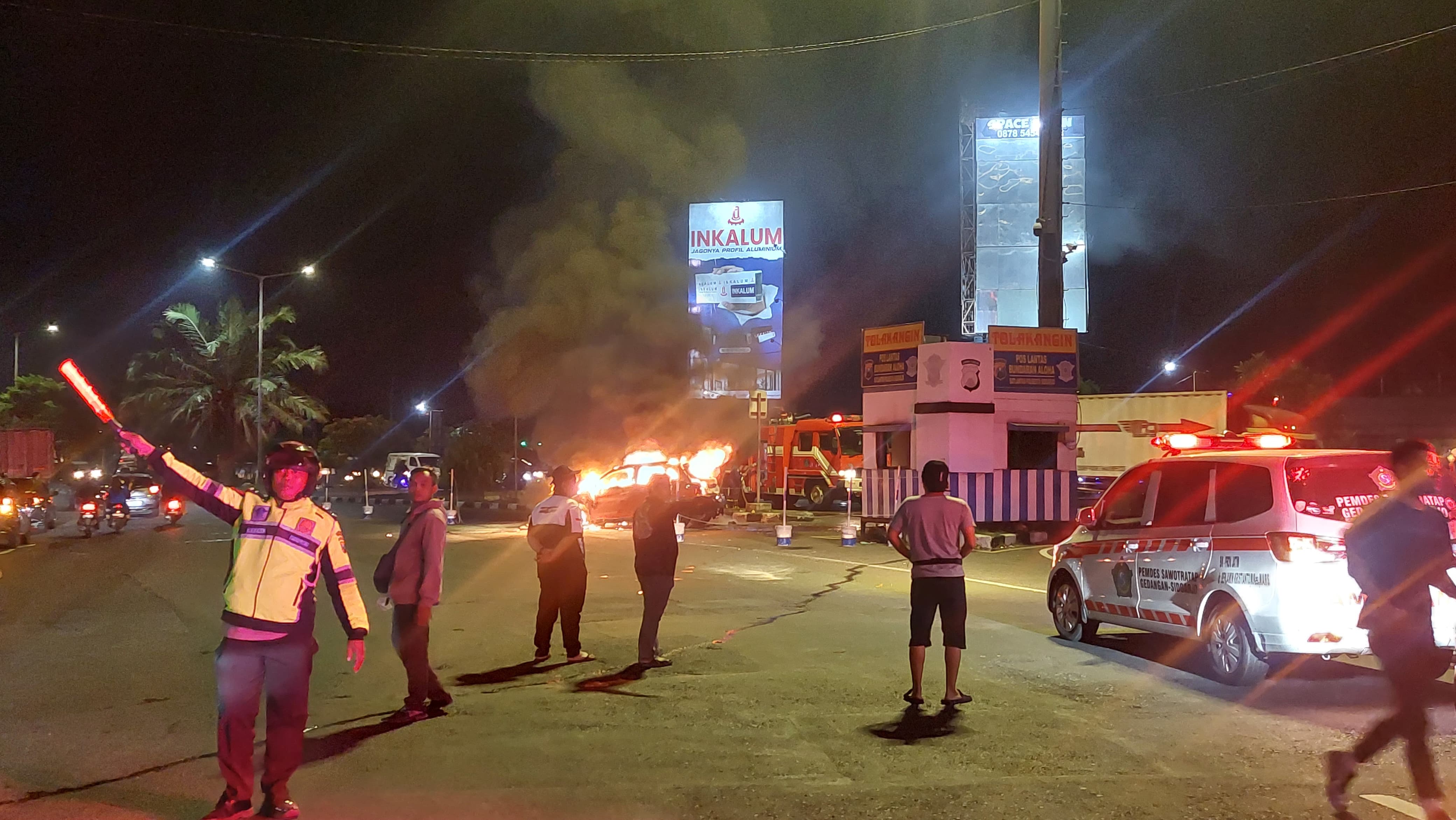 PEMADAMAN: Petugas berjibaku memadamkan mobil yang terbakar di Jalan Raya Aloha, Gedangan, Selasa (22/7).