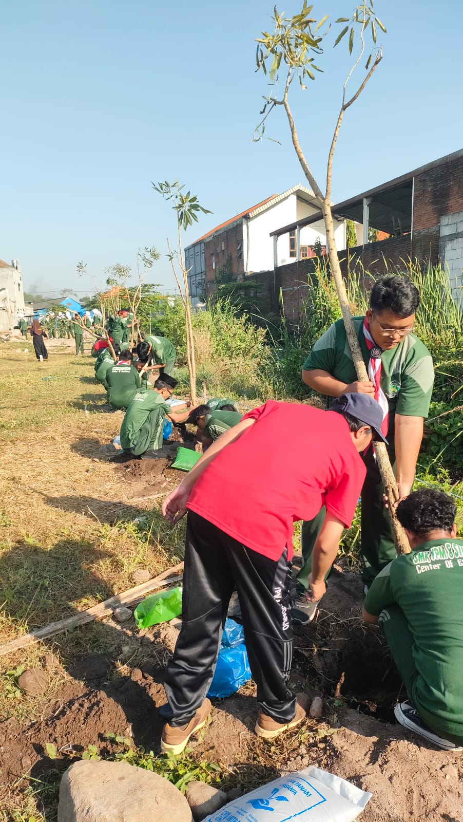 PEDULI LINGKUNGAN: Dewan guru dan siswa SMK YPM 8 Sidoarjo saat melakukan aksi penanaman pohon Tabebuya.(ANAS/RADAR SIDOARJO)&nbsp;