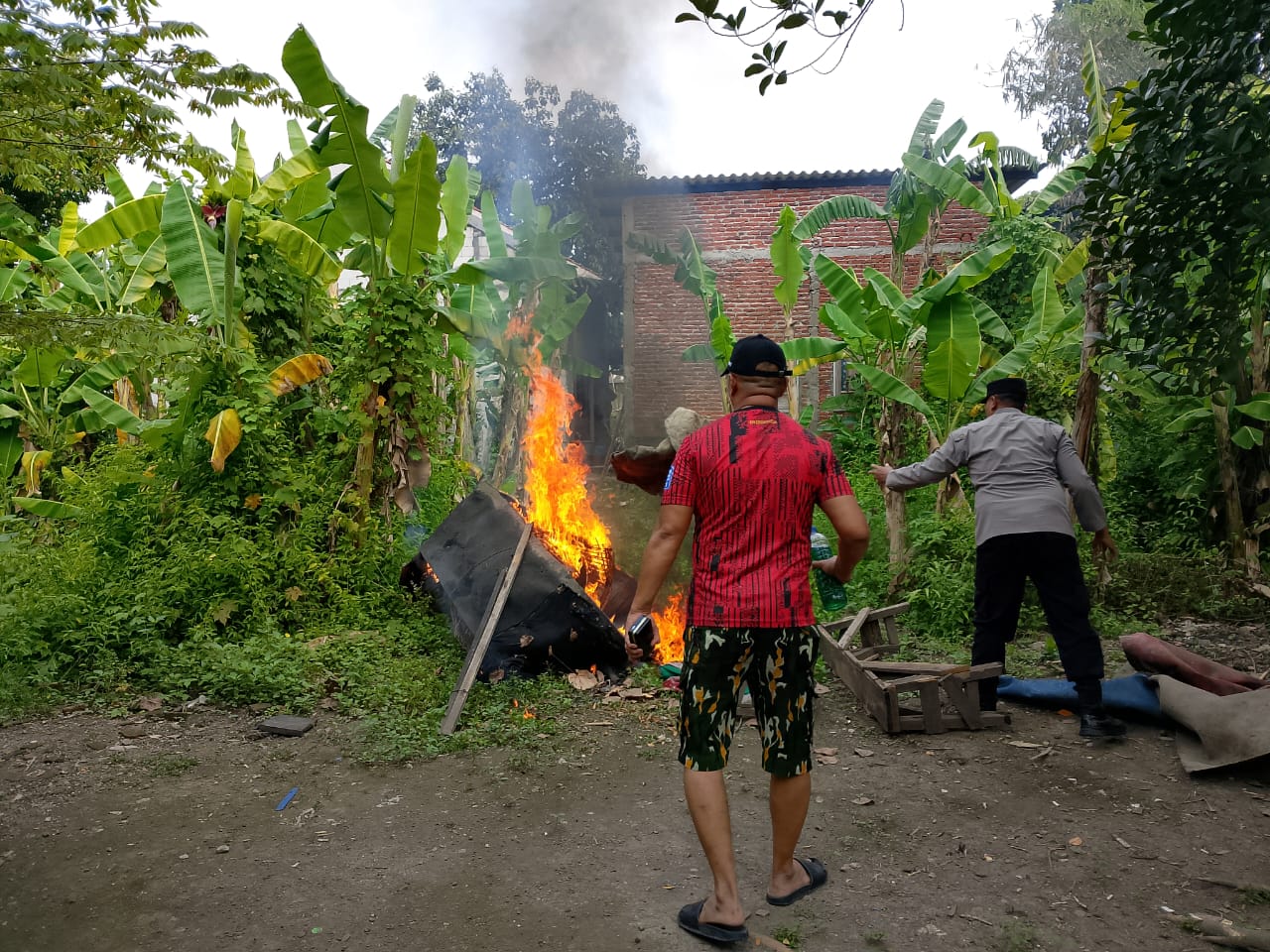 MEMBARA: Polisi membakar perlengkapan di arena judi sabung ayam di Sukodono, Sidoarjo.