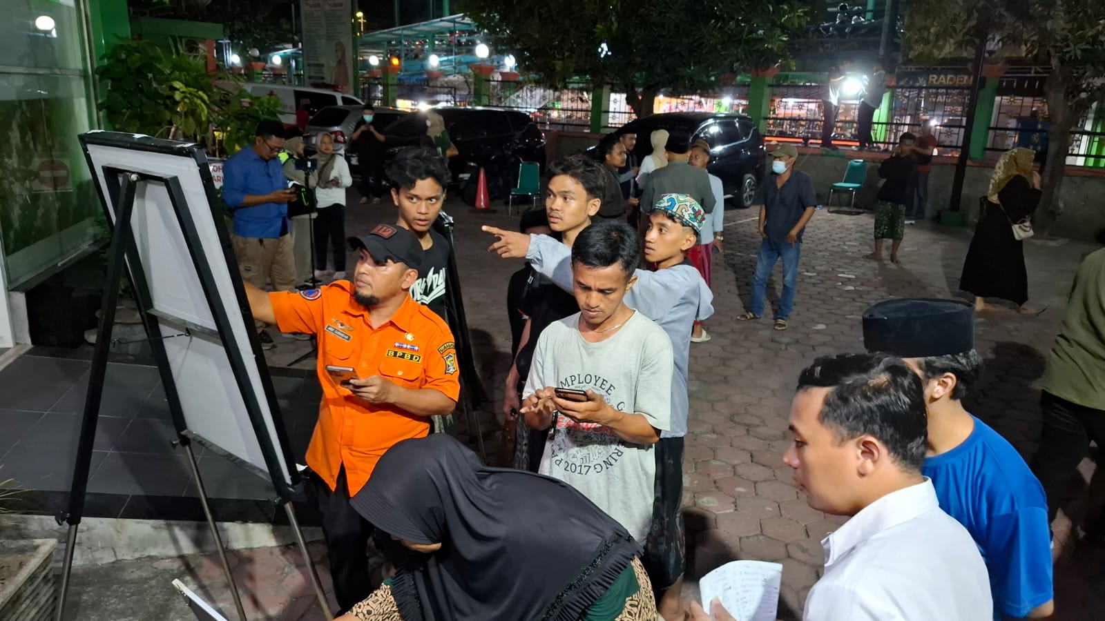 PANIK: Keluarga korban terlihat mencermati data daftar korban ambruknya Musala Ponpes Al Khoziny Buduran yang ditempel di RSI Siti Hajar. (M SAIFUL ROHMAN/RADAR SIDOARJO)