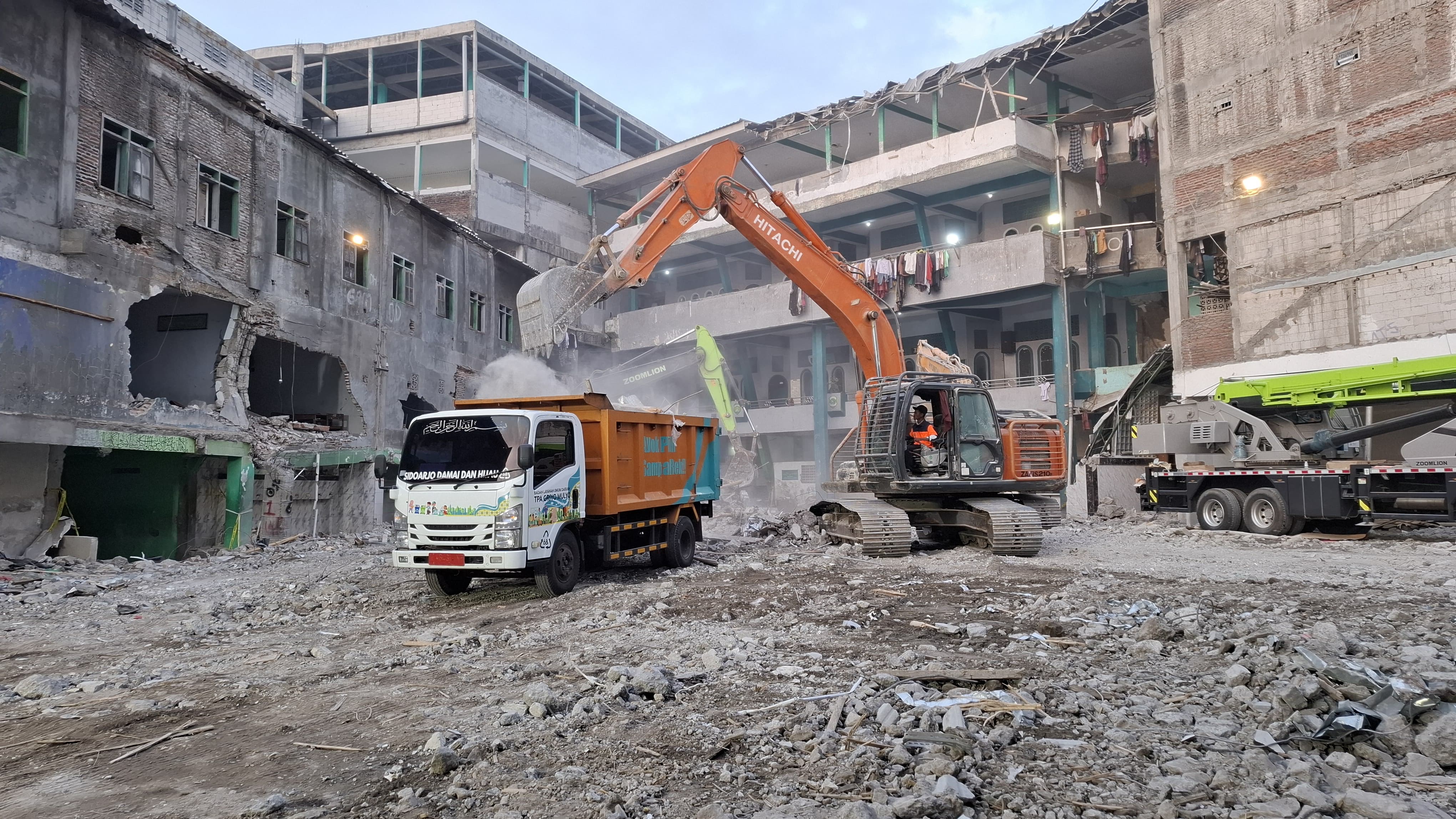 TUNTAS: Petugas DLHK Sidoarjo saat memuat material reruntuhan bangunan ke dalam dump truk di area Pondok Pesantren Al-Khoziny, Buduran. (M SAIFUL ROHMAN/RADAR SIDOARJO)