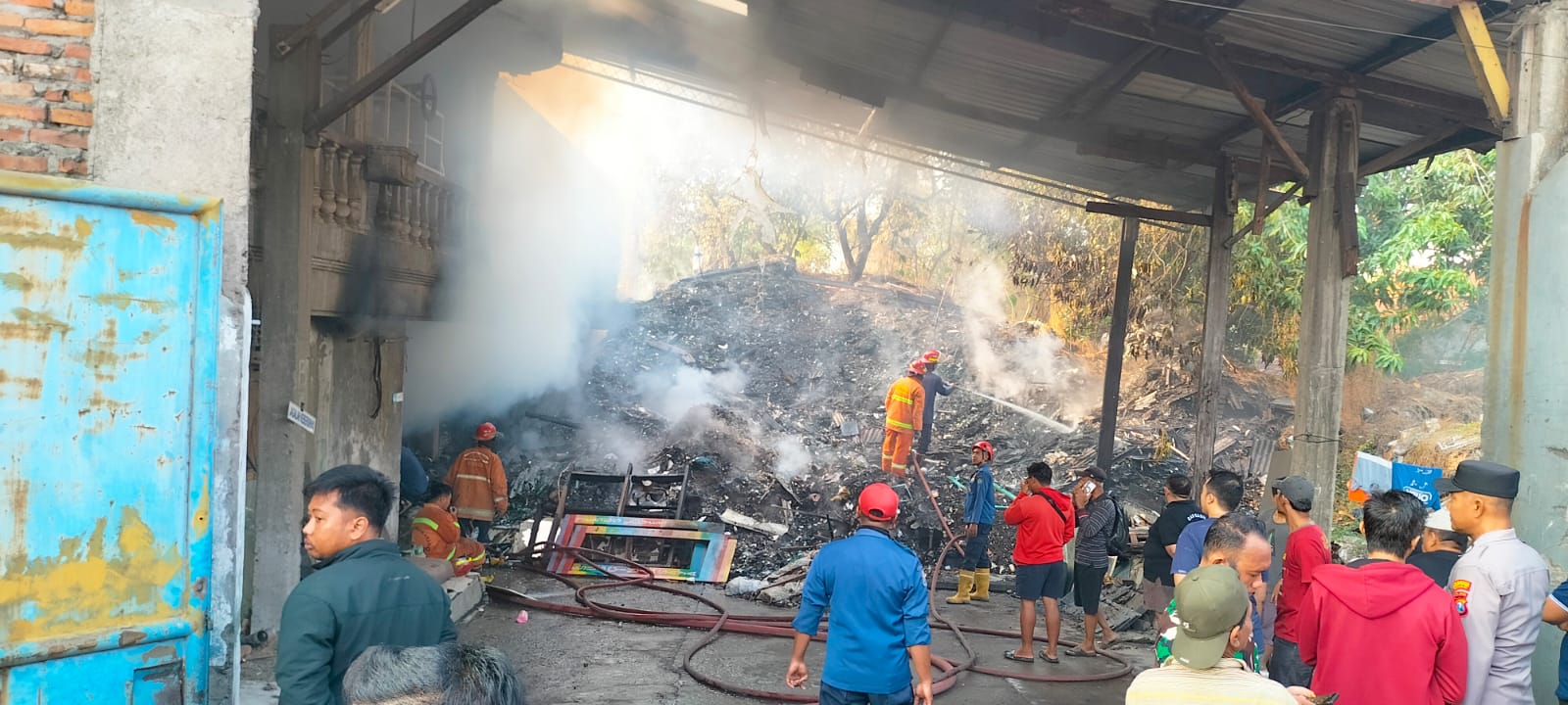 PEMBASAHAN: Petugas pemadam berjibaku memadamkan api di gudang kawasan Kletek, Taman, Sidoarjo, Selasa (14/10) pagi. (DIKY SANSIRI/RADAR SIDOARJO)