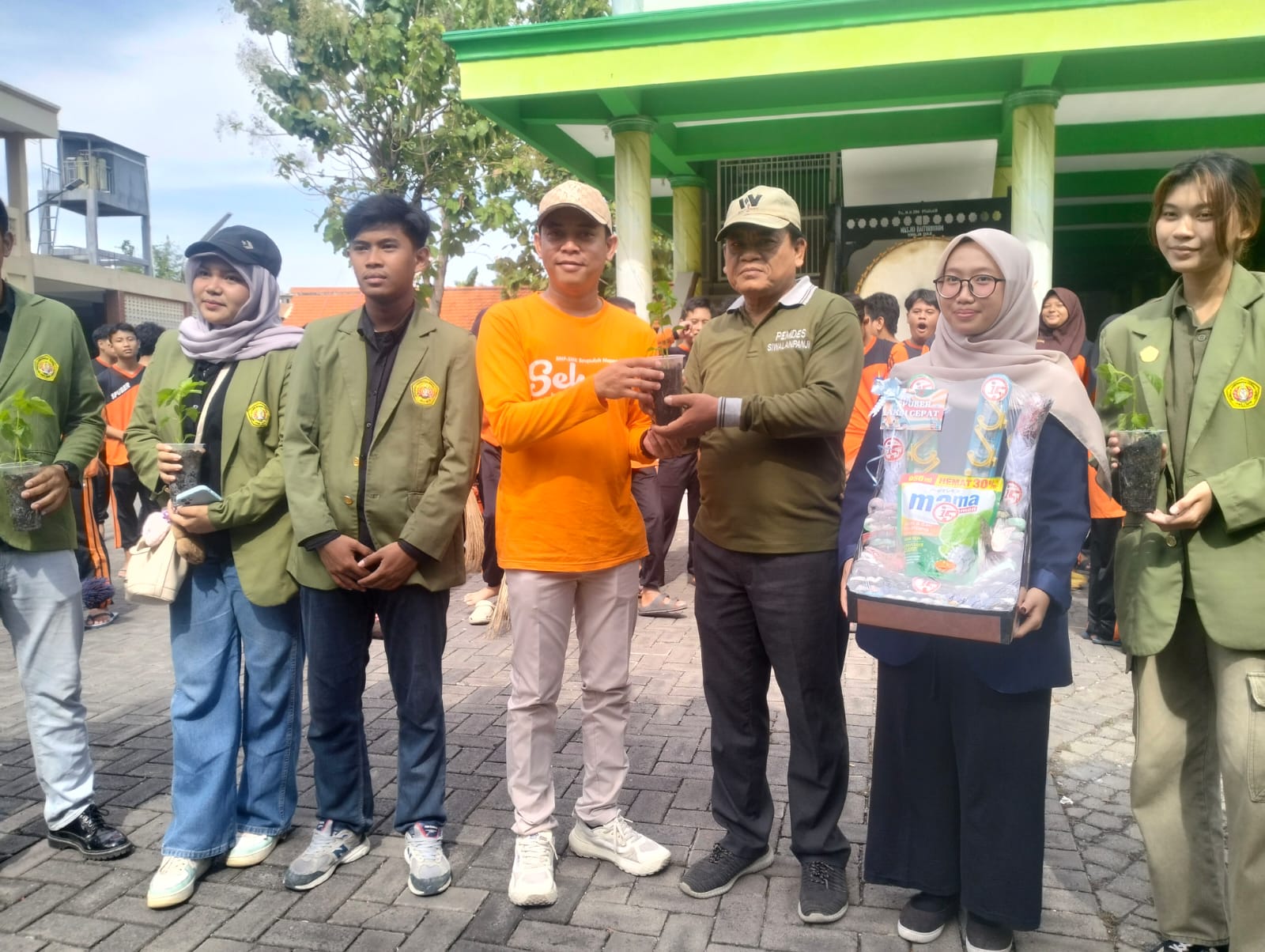 SIMBOLIS: Kepala Sekolah SMP Sepuluh Nopember Sidoarjo Saiful Tulus Jatmika, S.Pd., M.Pd.memberikan bibit tanaman ke perwakilan Desa Siwalanpanji. (ANAS/ RADAR SIDOARJO)
