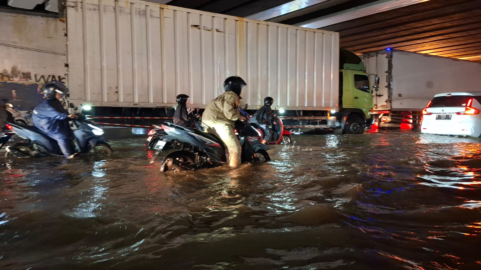 HATI-HATI: Pengendara motor melintasi genangan air di bawah jalan tol depan Lippo Plaza Sidoarjo. (M SAIFUL ROHMAN/RADAR SIDOARJO)