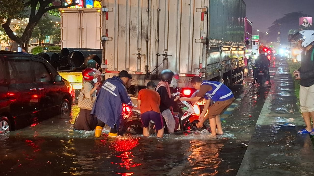 MESIN MATI: Sejumlah relawan mengamankan motor pengendara yang mogok ke atas trotoar. (M SAIFUL ROHMAN/RADAR SIDOARJO)