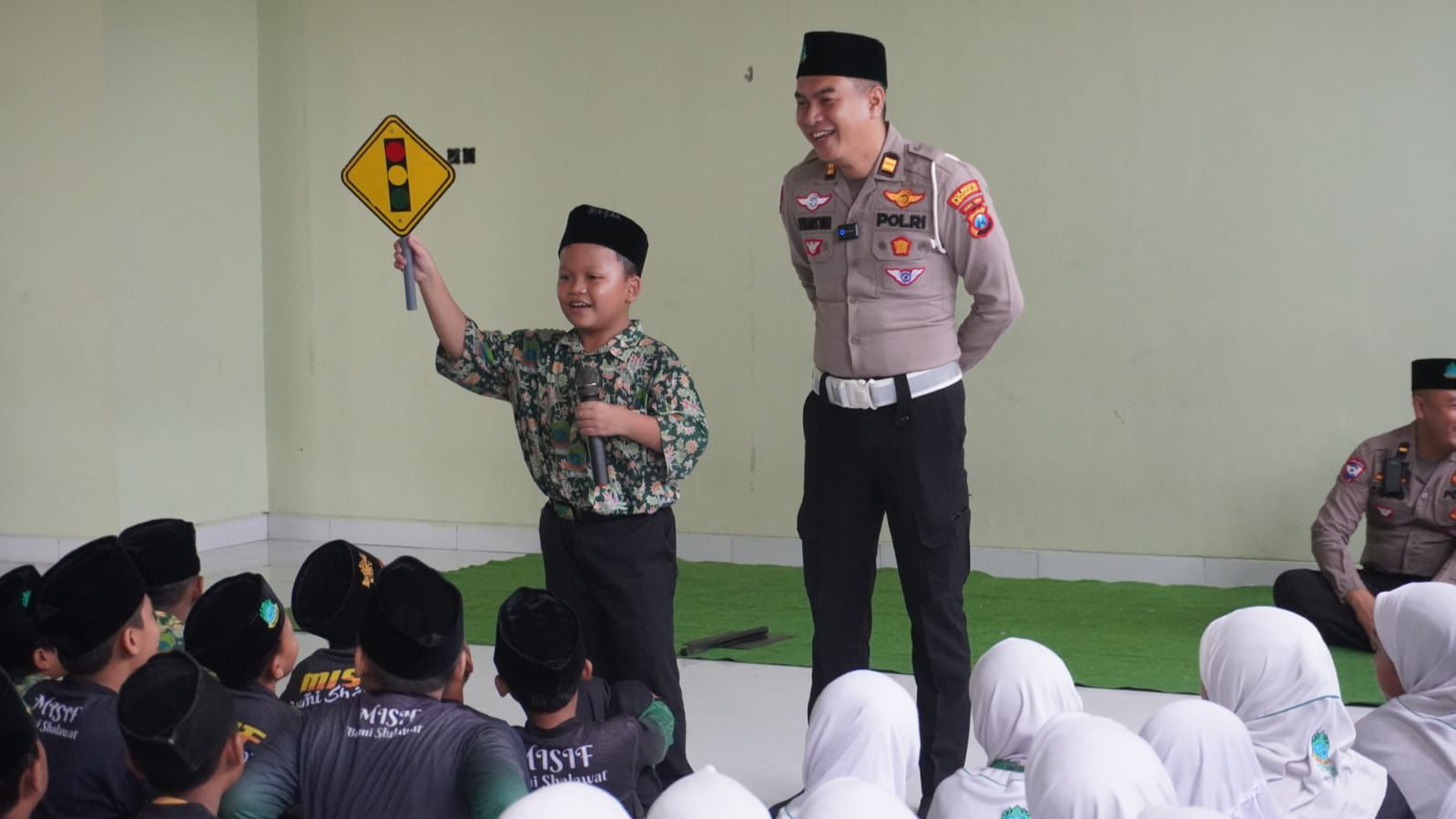 RIANG: Siswa MI belajar bersama anggota Satlantas Polresta Sidoarjo mengenal rambu-rambu lalu lintas. (IST/RADAR SIDOARJO)