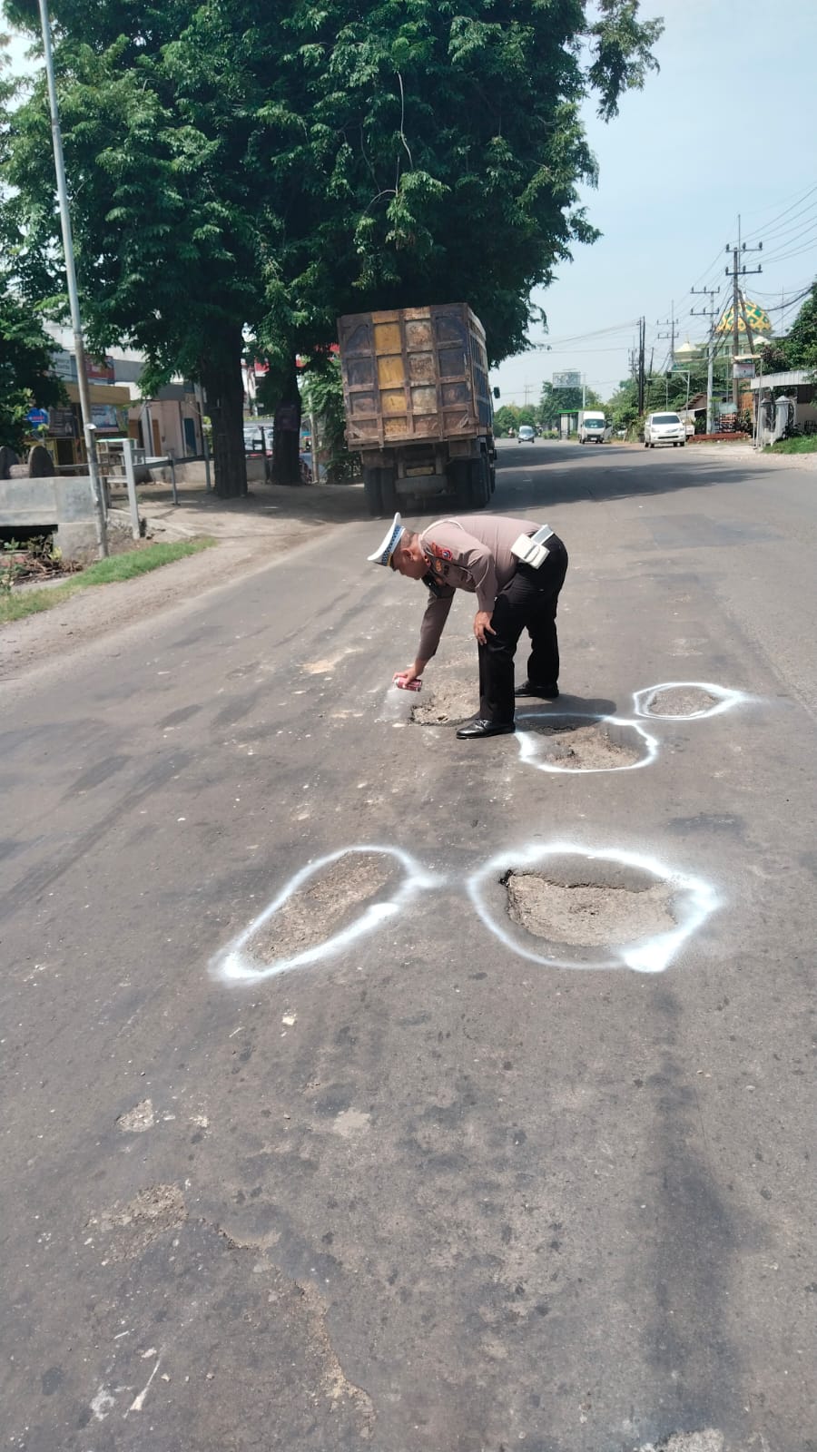 ANTISIPASI: Kanit Lantas Polsek Balongbendo Ipda Sugeng Hariyono menandai jalan berlubang di Jalan Raya Jabaran.