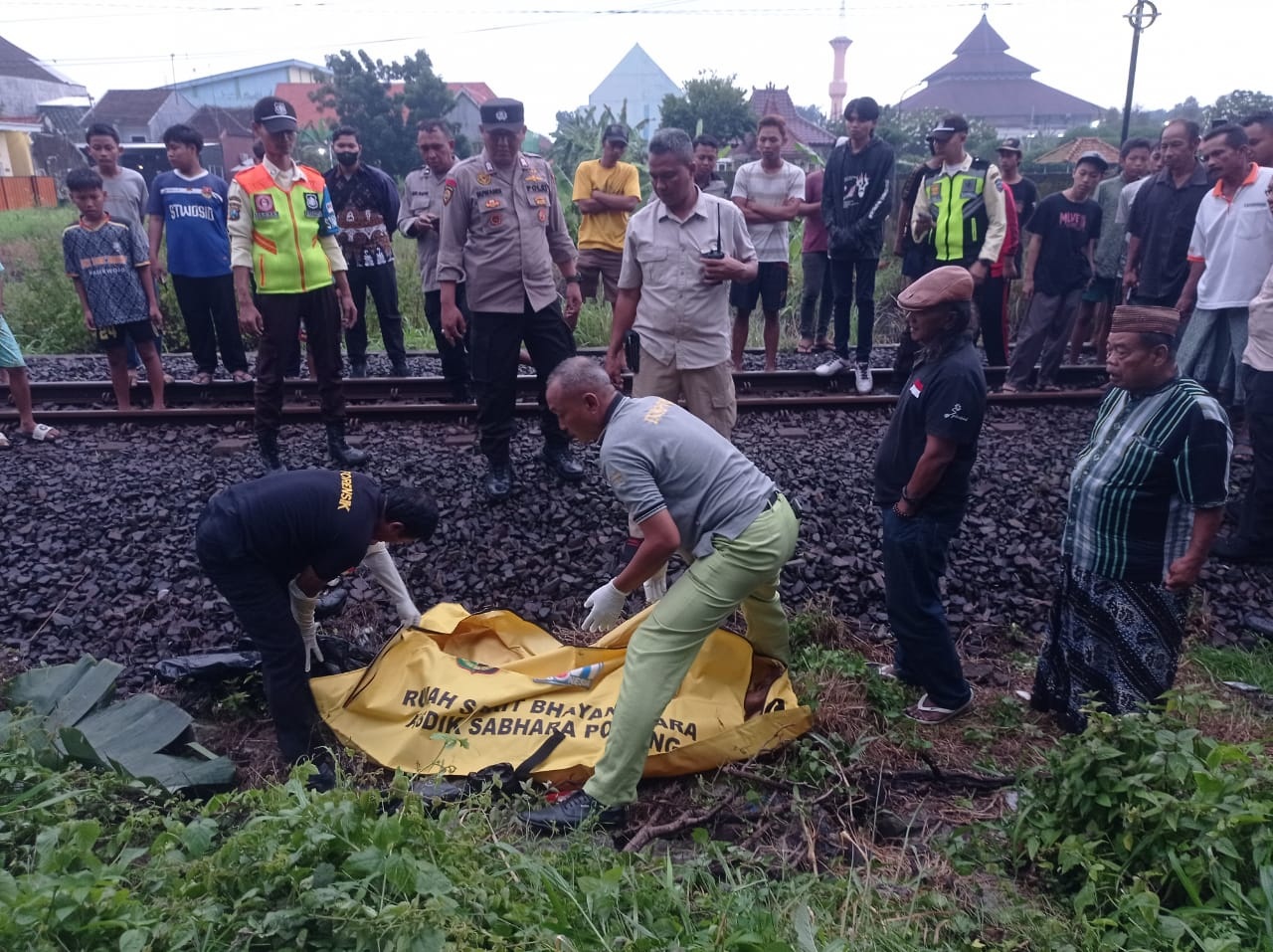 NAHAS: Petugas mengevakuasi jenazah korban yang tersambar kereta api di kawasan Perumahan Magersari. (SURYANTO/RADAR SIDOARJO)