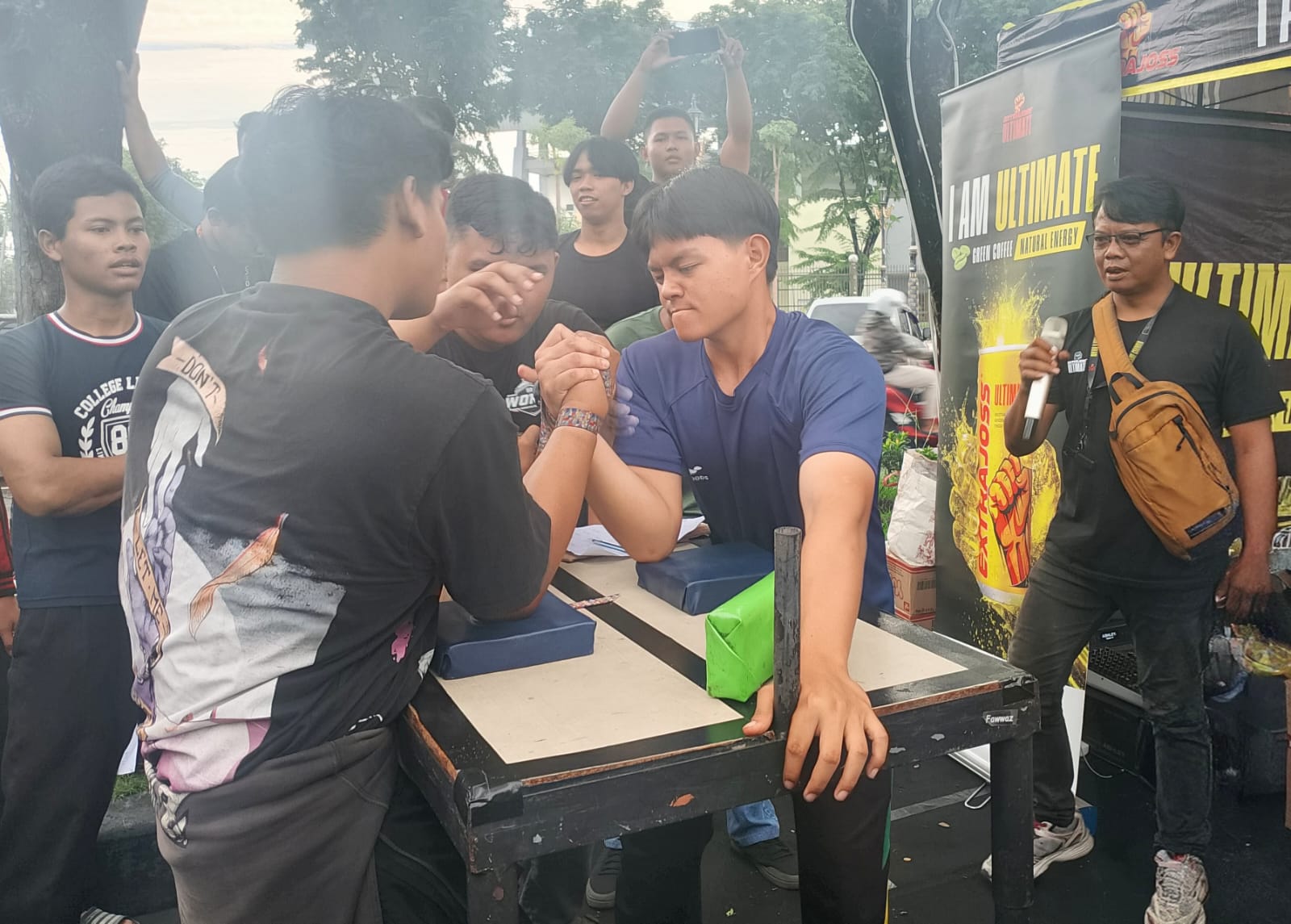 ADU KUAT LENGAN: Dua peserta saling adu kekuatan dalam laga adu panco yang menyedot perhatian pengunjung Car Free Day. Atmosfer penuh semangat menjadikan ajang hiburan dan unjuk sportivitas.