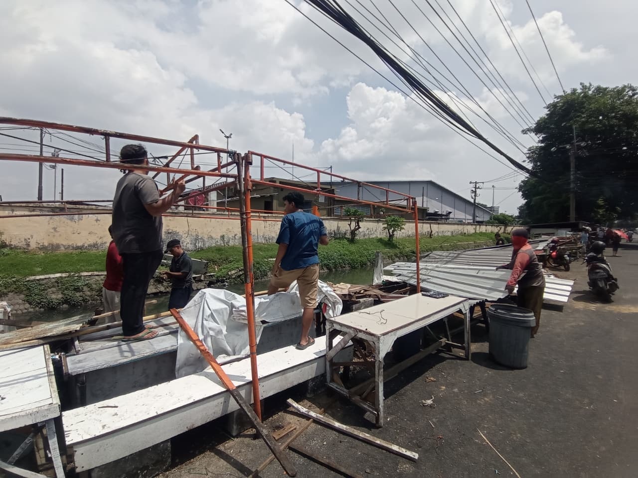 DIBANGUN LAGI: Sejumlah pedagang membangun kembali lapak miliknya yang sempat roboh akibat terpaan angin kencang di Desa Pepelegi, Kecamatan Waru, Sidoarjo. (SURYANTO/RADAR SIDOARJO)