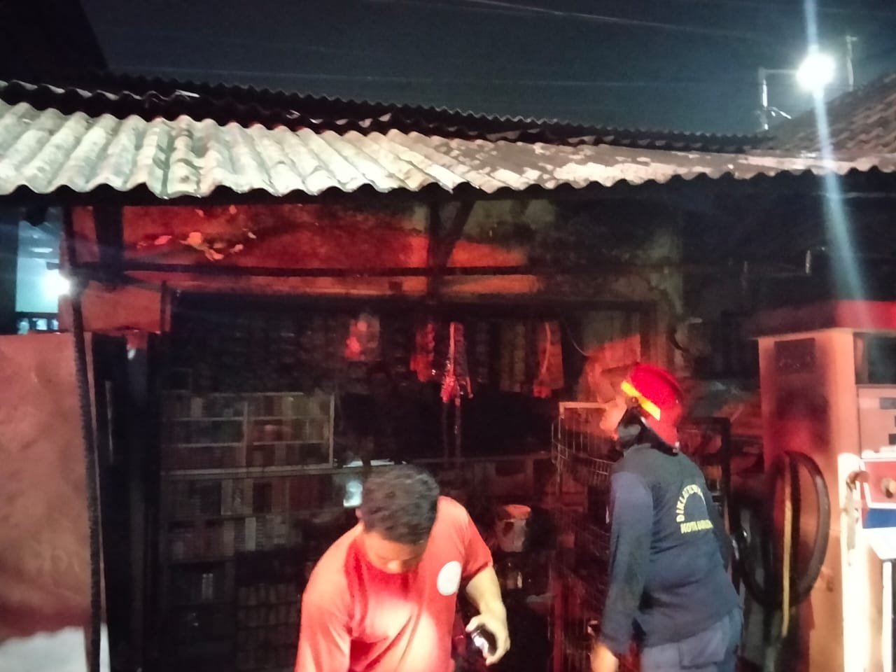 HANGUS: Petugas memadamkan motor yang terbakar di salah satu toko kelontong di Ngampelsari.