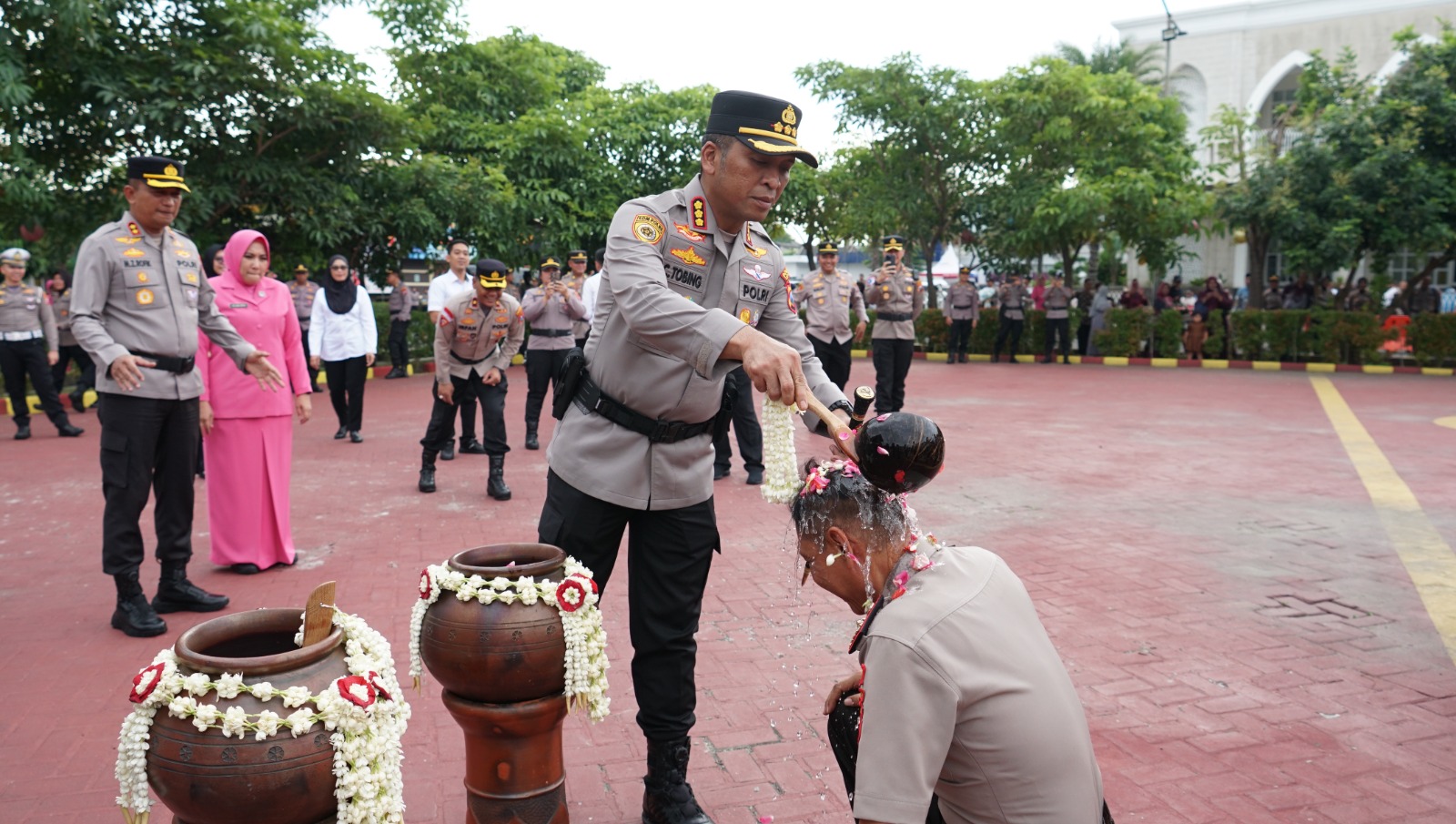 BERSYUKUR: Kapolresta Sidoarjo Kombespol Christian Tobing menyiramkan air kembang ke salah satu anggota yang naik pangkat.