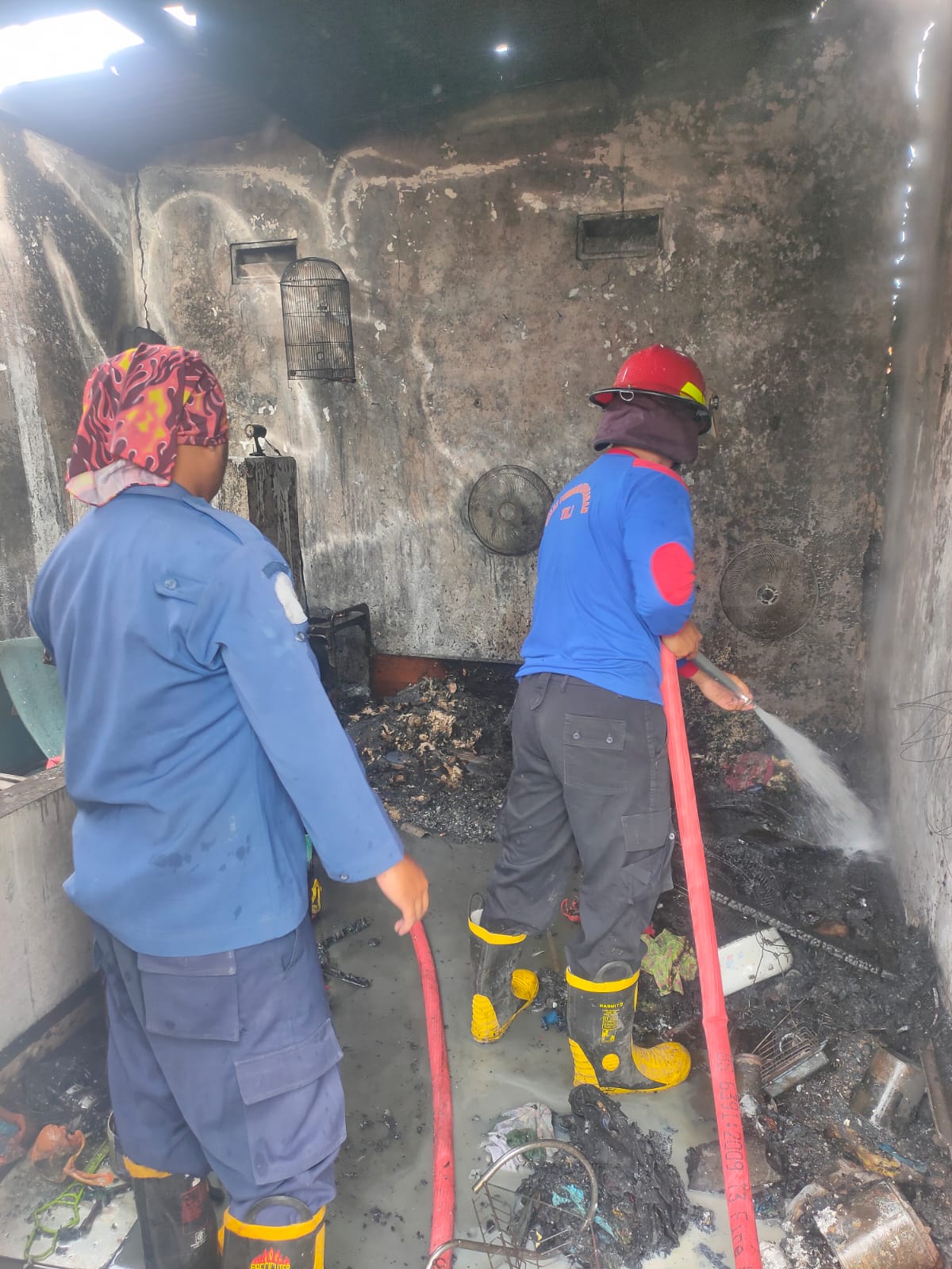 PADAM: Petugas melakukan pembasahan saat kebakaran terjadi di sebuah rumah di Desa Sidodadi, Taman, Sidoarjo.