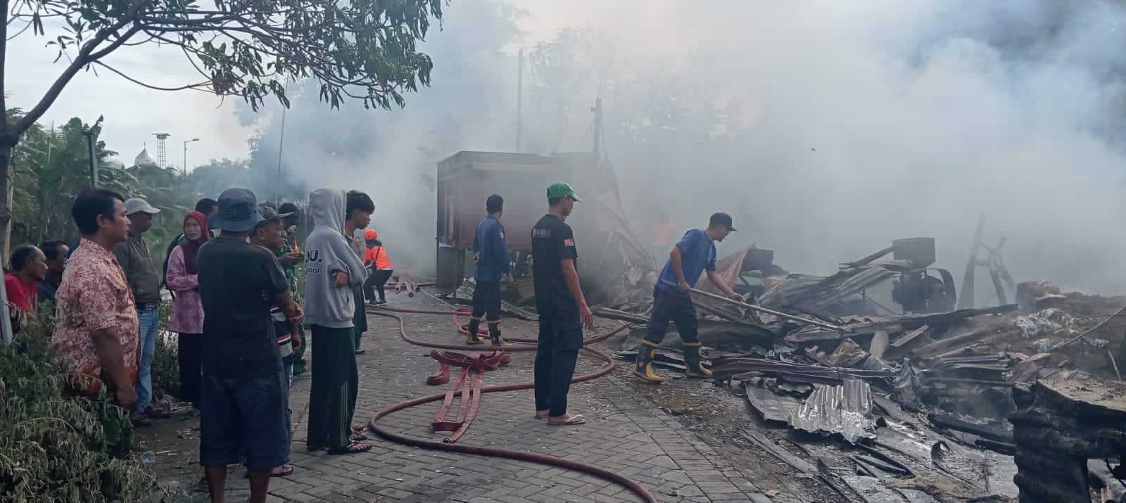PEMBASAHAN: Petugas berusaha memadamkan api saat kebakaran melanda gudang pakan ternak di Prambon, Sidoarjo.